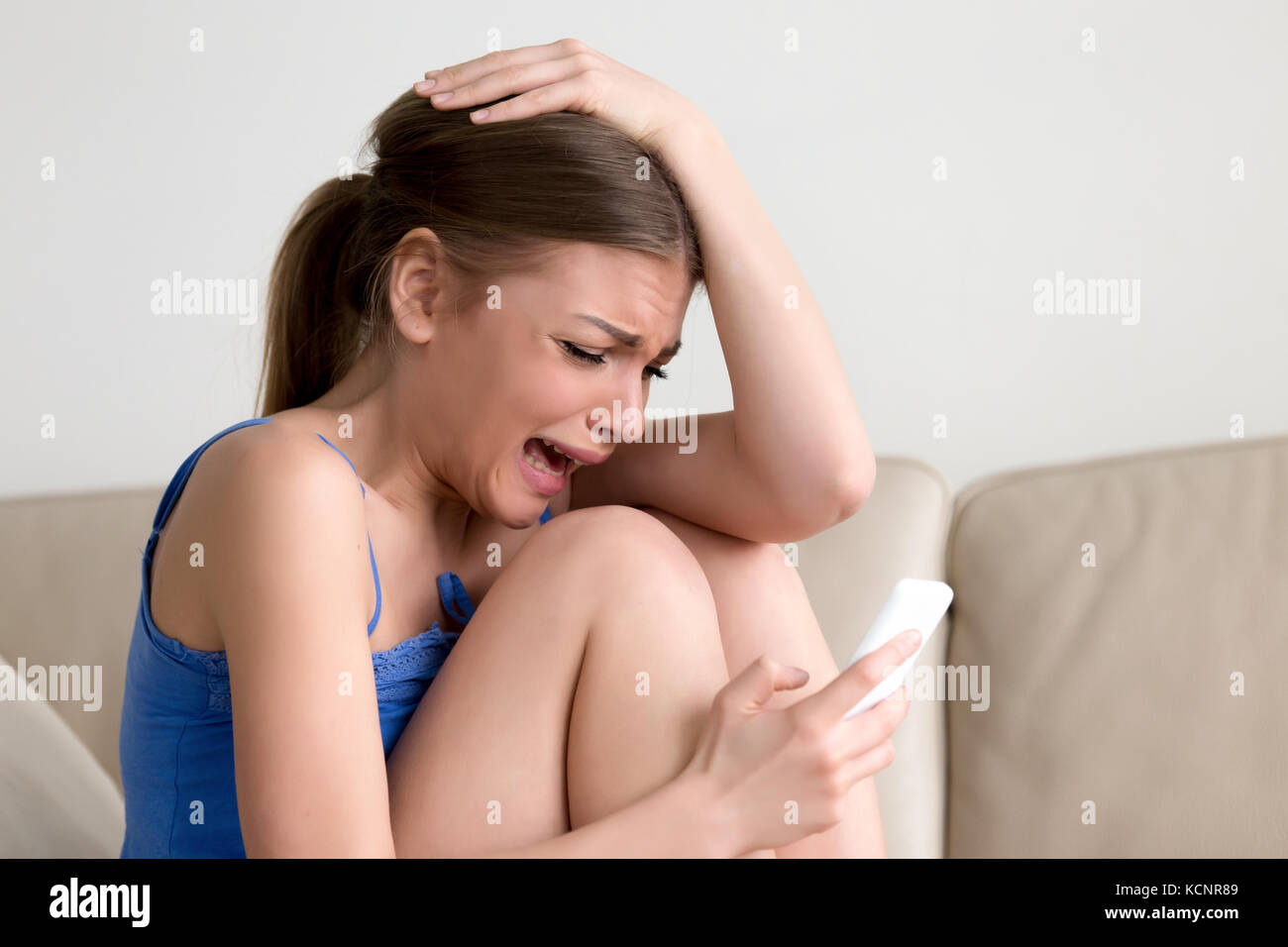 Schluchzend jugendlich Mädchen Messaging auf Telefon, Weinen gedrückt junge Dame hält Telefon sitzen auf einem Sofa, frustrierte Frau in Tränen auf Zelle Gefühl rejec Stockfoto