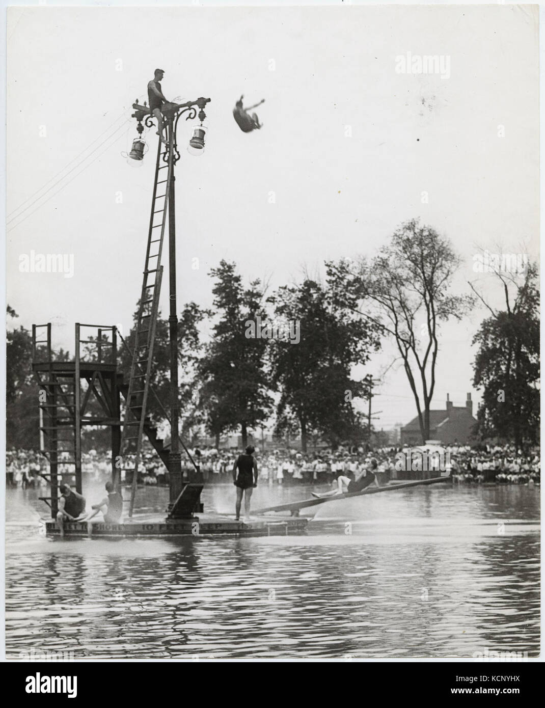 Tauchen Taucher improvisieren eine hohe Plattform von der Spitze eines Lichtmast am Messegelände Park Pool Stockfoto