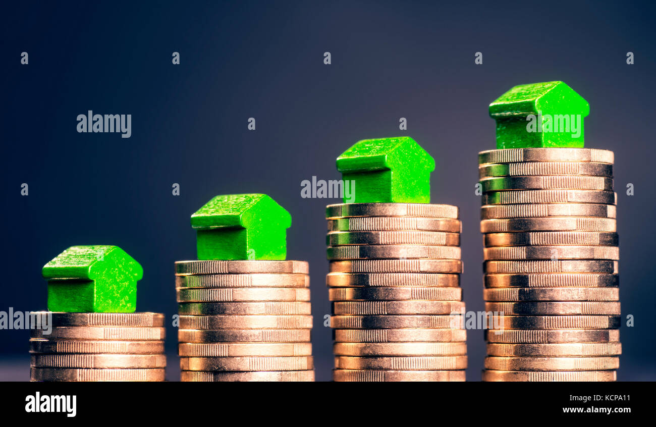 Kleine grüne Häuser stehen auf Stapel von Münzen. Stockfoto