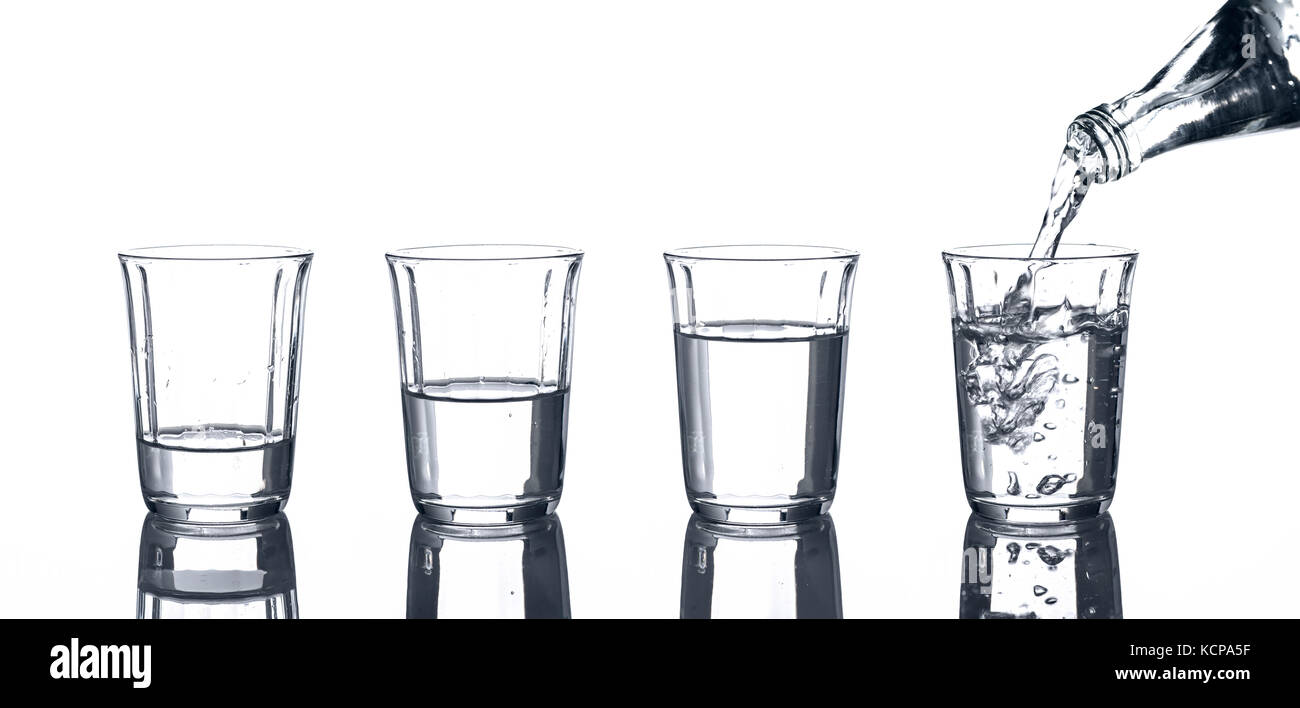 4 Gläser mit Wasser und eine Flasche von dem gegossen wird. Stockfoto