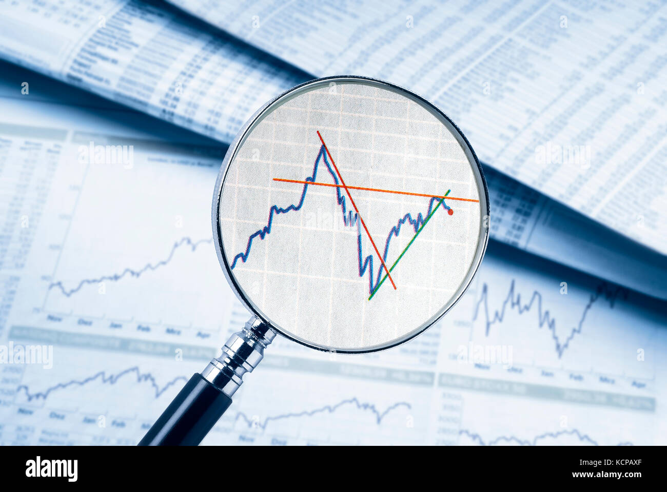 Lupe zeigt eine Aktie. Im Hintergrund der Tabellen und Diagramme können gesehen werden. Stockfoto