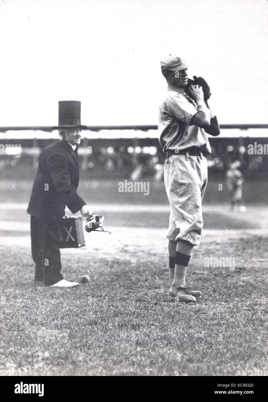 Dieses Bild zeigt einen Clown hinter dem Pitcher für die Pittsburgh Pirates bei einem Eröffnungstag 1912 im Robison Field. Es ist auch ein wahrscheinlicher Auftritt von Claude Hendrix, einem Pitcher für die Piraten. Stockfoto
