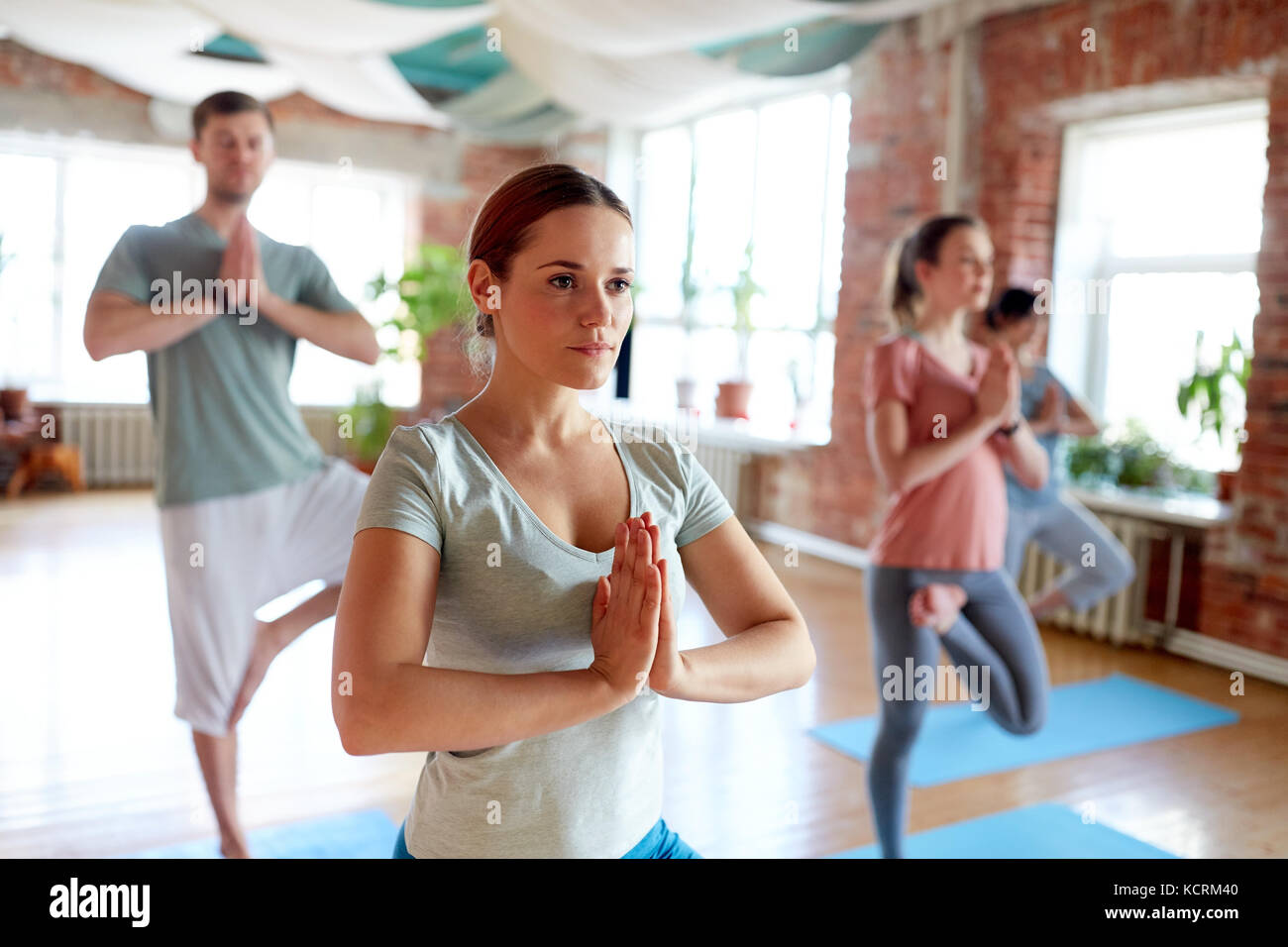 Gruppe von Menschen, die Yoga die Baumhaltung im Studio Stockfoto