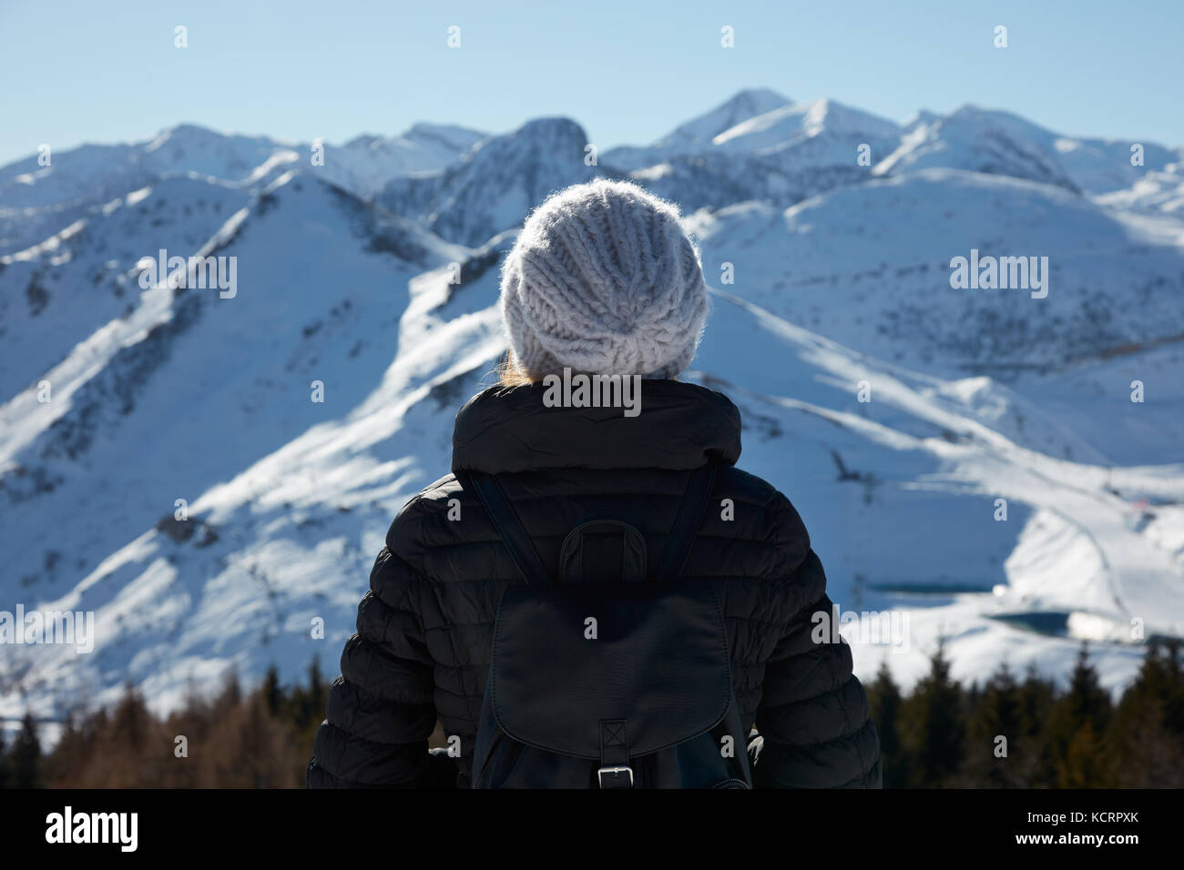 Frau mit Wolle hat Blick auf die Berge mit Schnee an einem sonnigen Wintertag Stockfoto