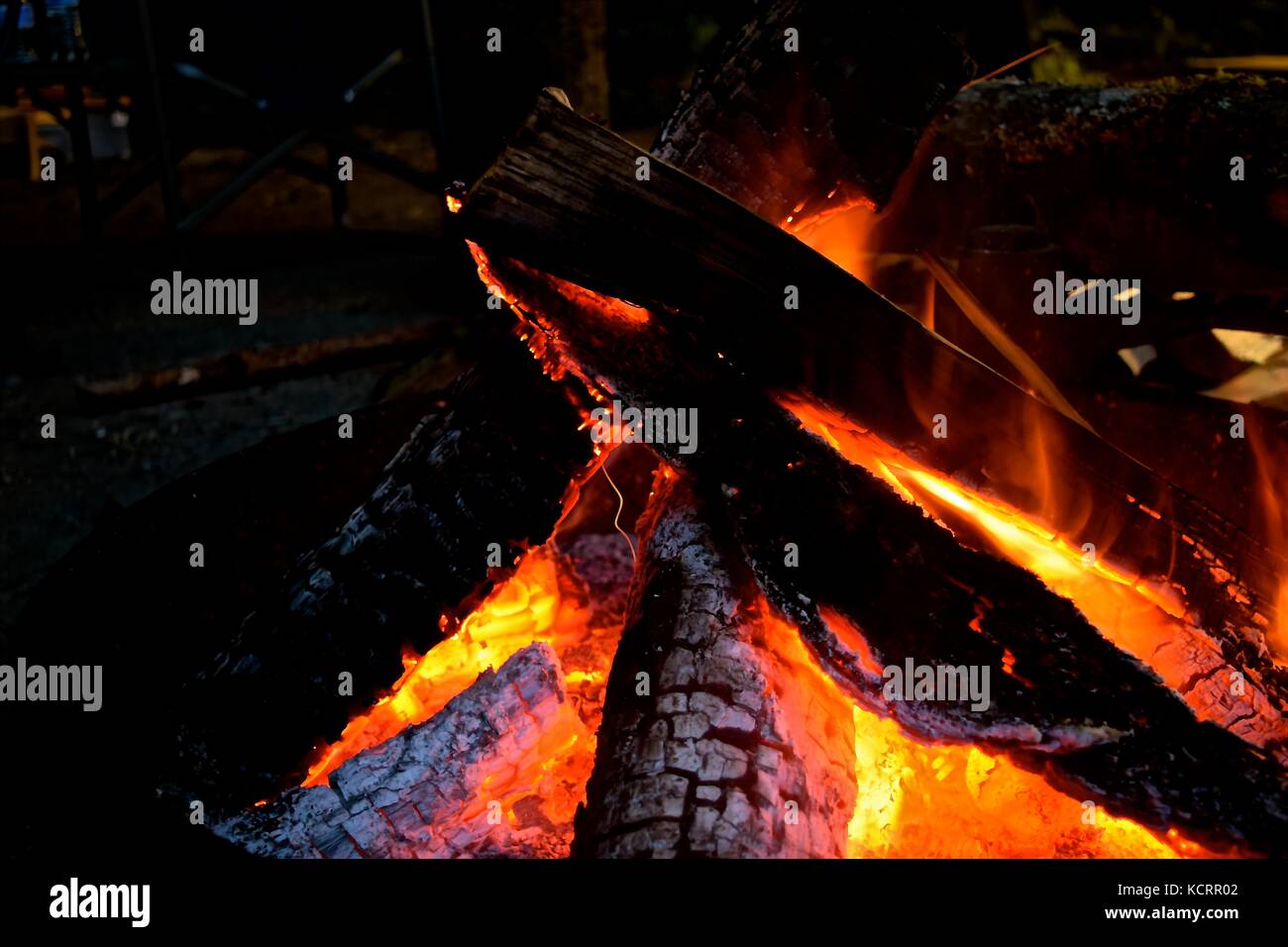 Eine hypnotisierende Lagerfeuer auf einer kühlen Nacht der Campingplatz bringt Wärme und sammelt Menschen um. Stockfoto