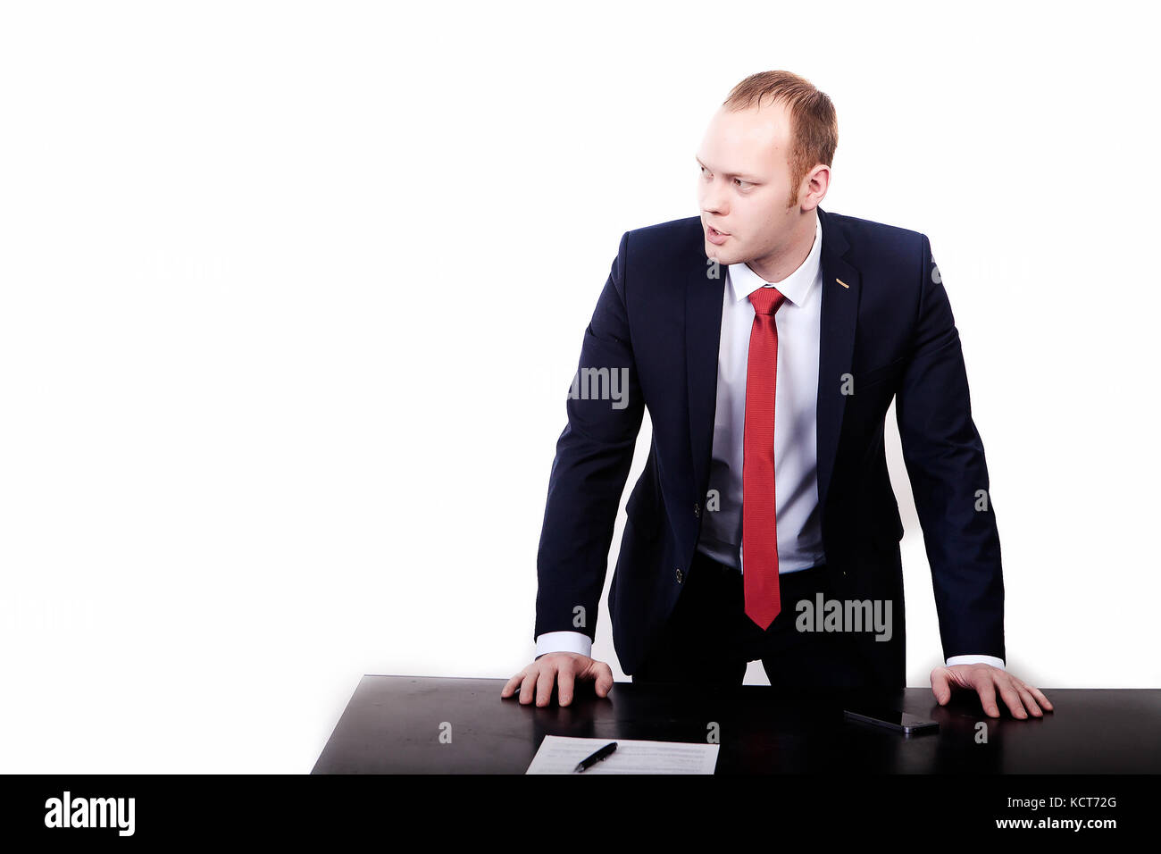 Architekt in einem schwarzen Anzug auf einem Schreibtisch mit einem Grundriss auf schiefen. weg schauen. Vor weißem Hintergrund. Stockfoto