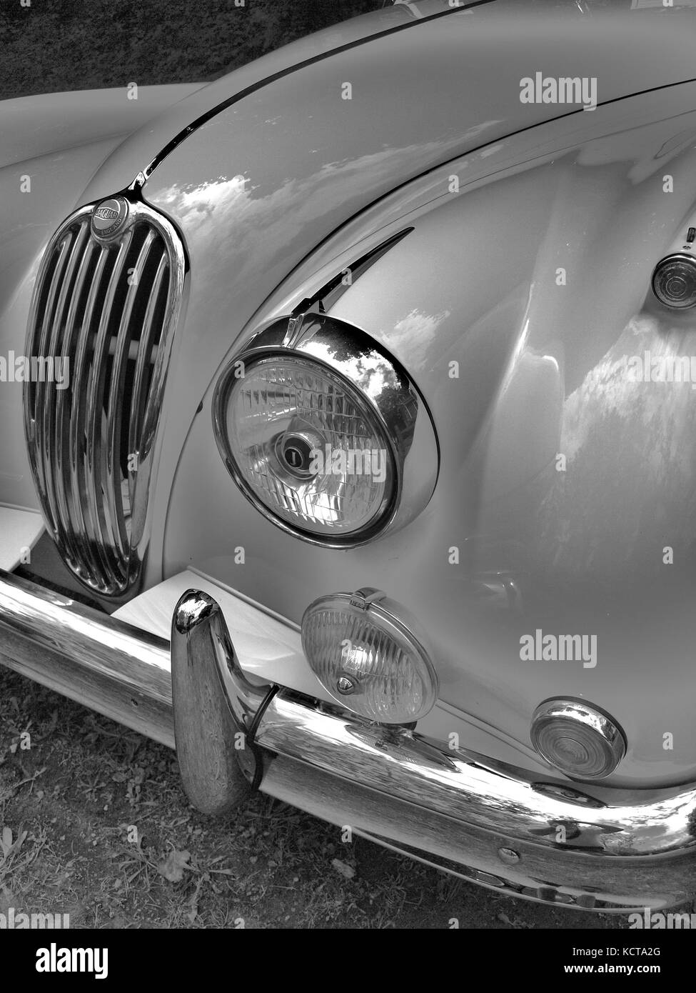 Jaguar XK-150 auf der lokalen Automobilmesse in B&W. Detail der Vorderseite des Autos und elegante Chrom-Grill und Rundleuchten. Stockfoto