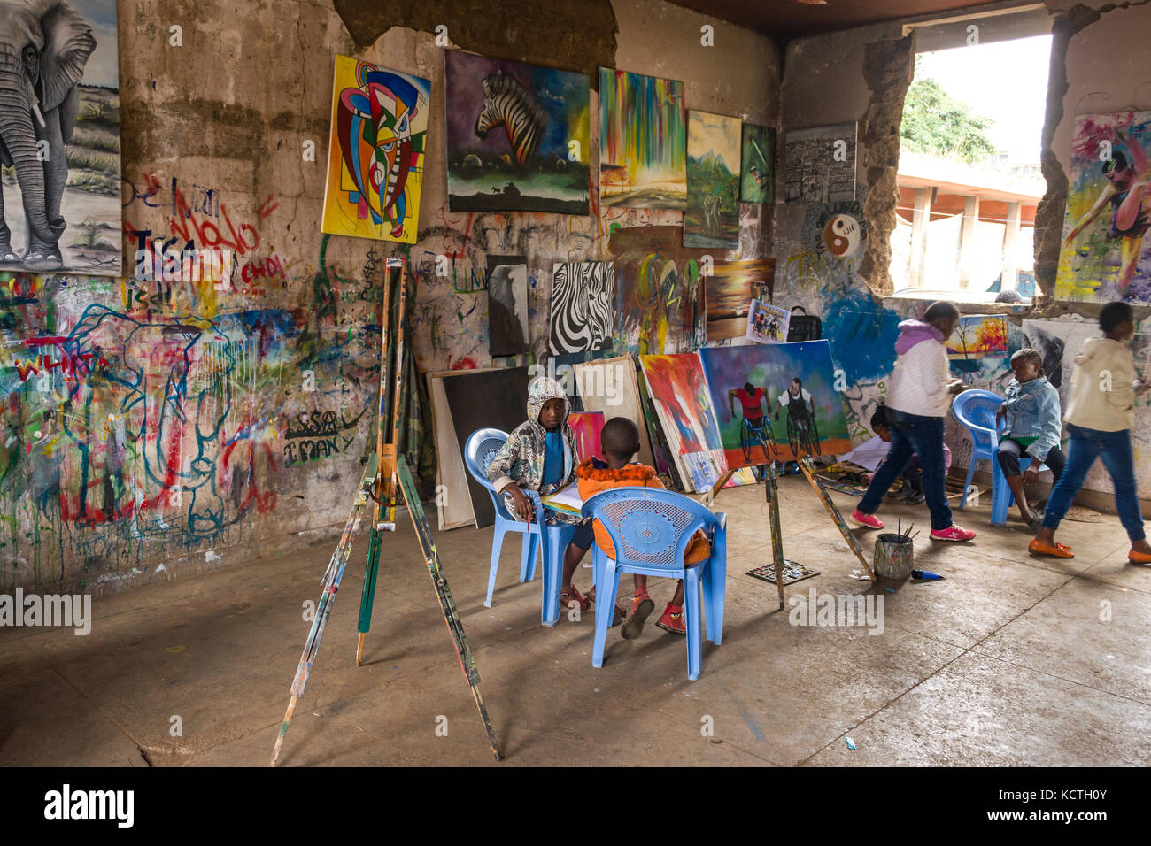 Junge afrikanische Kinder Praxis Zeichnen und Malen mit Kunstwerken an den Wänden der baufälligen Gebäude, Slum Kibera, Nairobi, Kenia Stockfoto