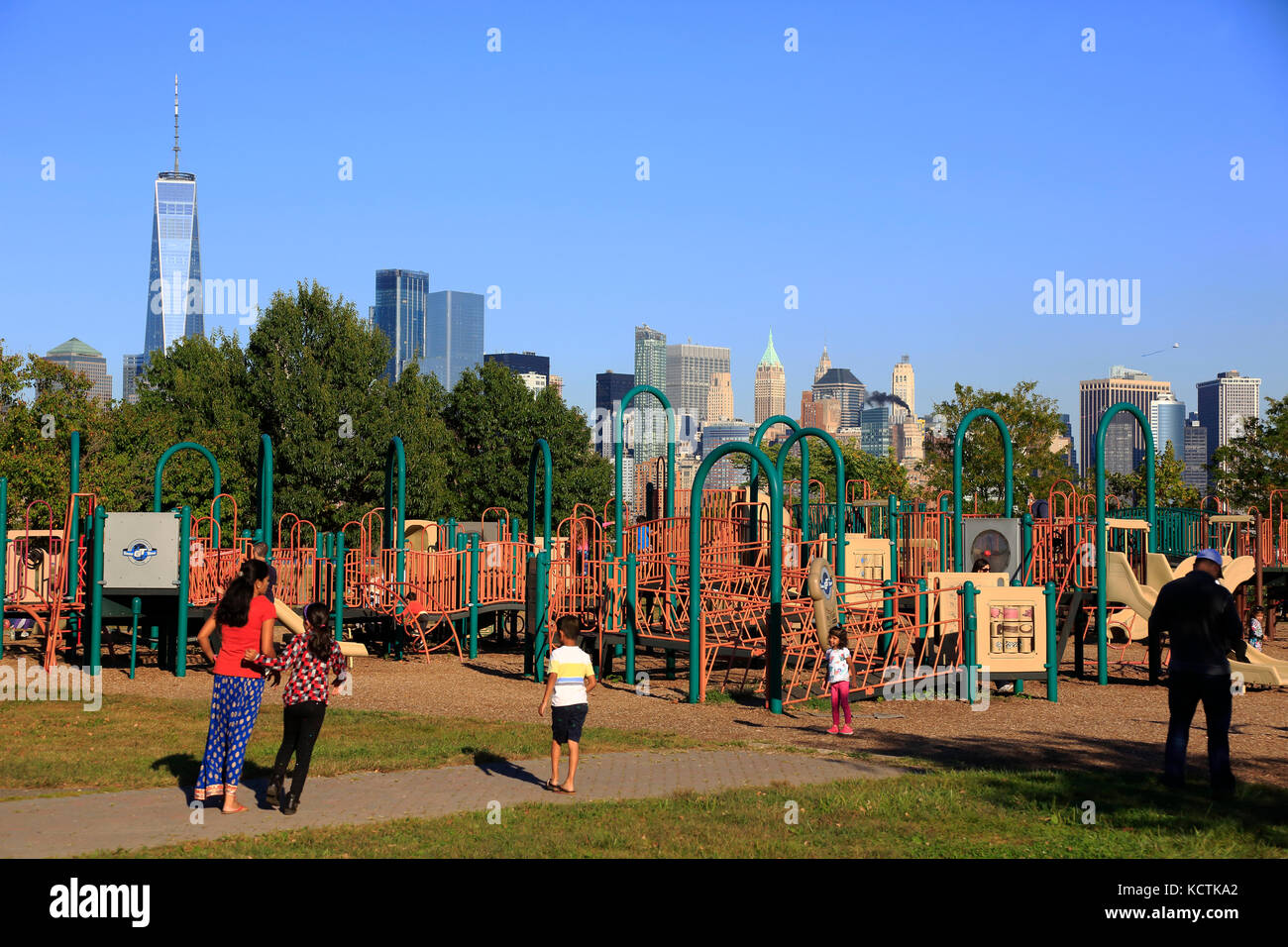 Kinder spielen am Spielplatz im Liberty State Park mit Skyline von Lower Manhattan und Freedom Tower im Hintergrund. New Jersey USA Stockfoto