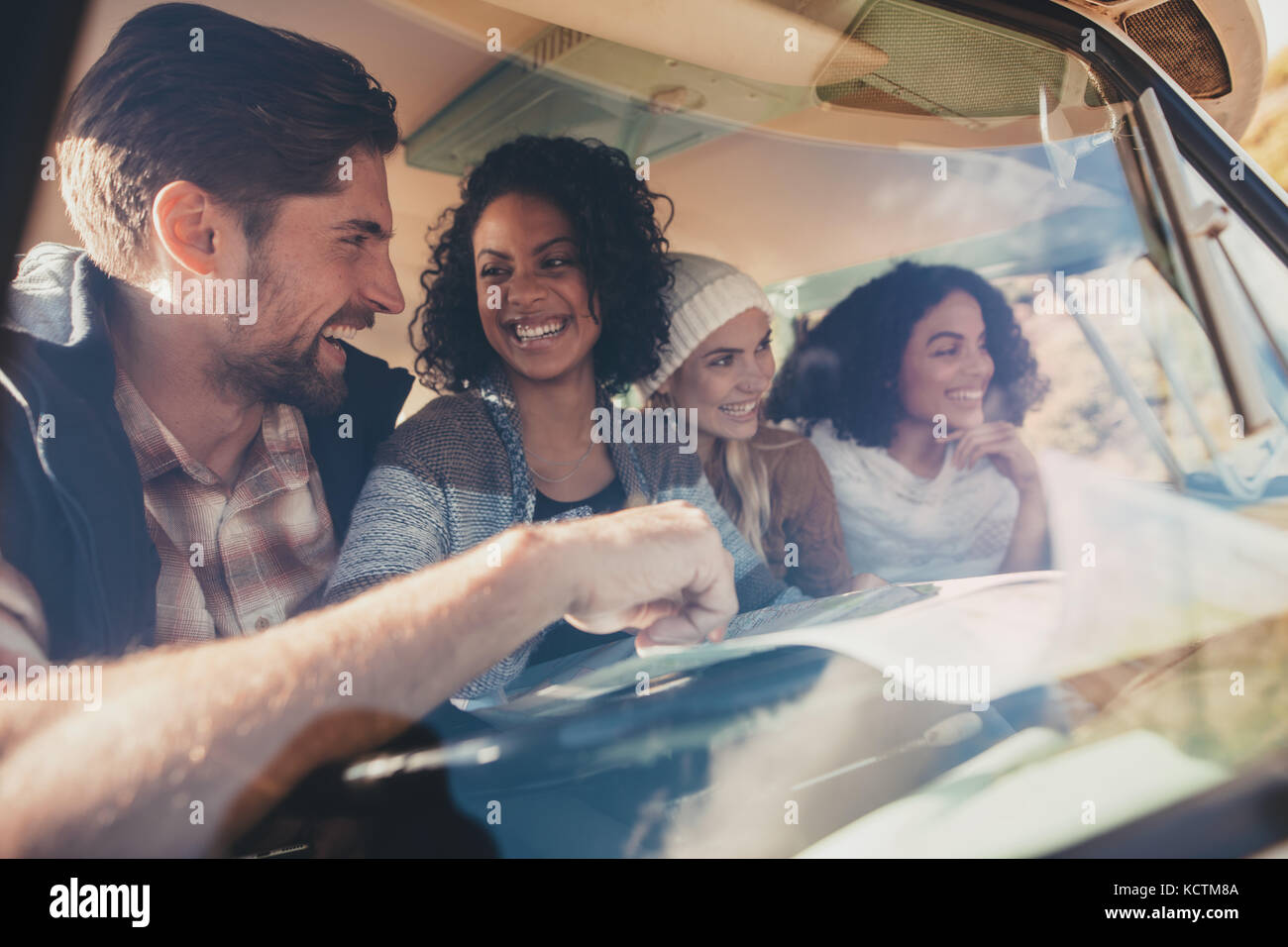 Gruppe von Freunden in einem Van mit Karte unterwegs. Mann diskutieren Reise Route mit weiblichen Freunde mit einer Karte. Stockfoto
