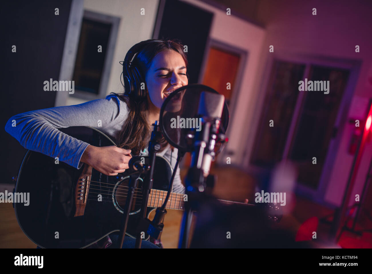 Female Vocal Artist Singen in einem Tonstudio mit Gitarre. Frau Sänger singt ein Lied und Gitarre zu spielen. Stockfoto
