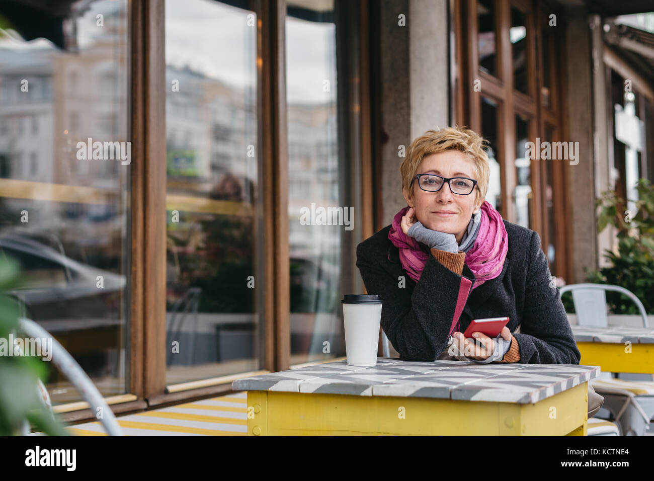 Verträumte Frau mit Telefon im Cafe Stockfoto