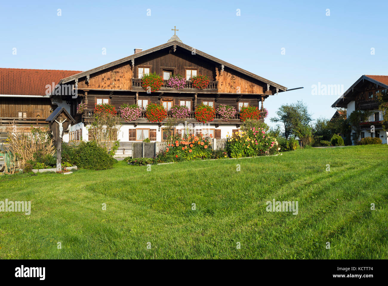 Bauernhof Häuser mit Holzfassade im traditionellen bayerischen Stil in Oberbayern mit blühenden Blumen in der Morgensonne, Irschenberg, Bayern, Deutschland Stockfoto
