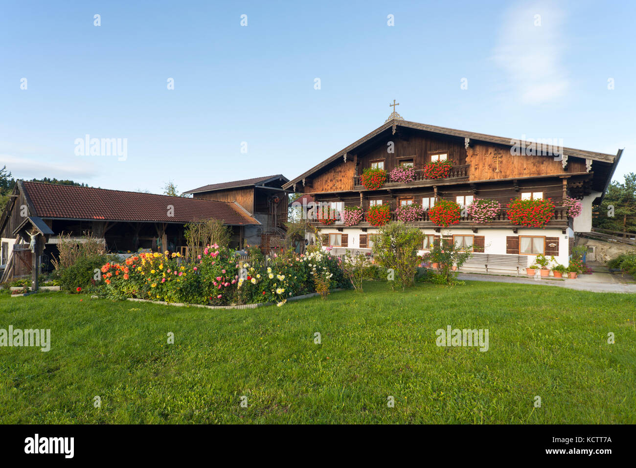 Bauernhof Häuser mit Holzfassade im traditionellen bayerischen Stil in Oberbayern mit blühenden Blumen in der Morgensonne, Irschenberg, Bayern, Deutschland Stockfoto