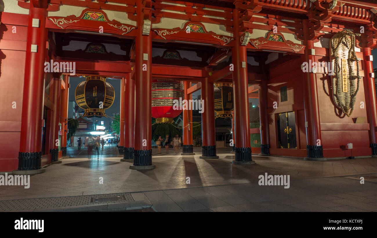 Horizontale Bild des Eingangstor Sensoji-tempel Schuß in der Nacht mit großen Laternen, rote Säulen und Schatten und verschwommenes Touristen unter Laternen. Stockfoto