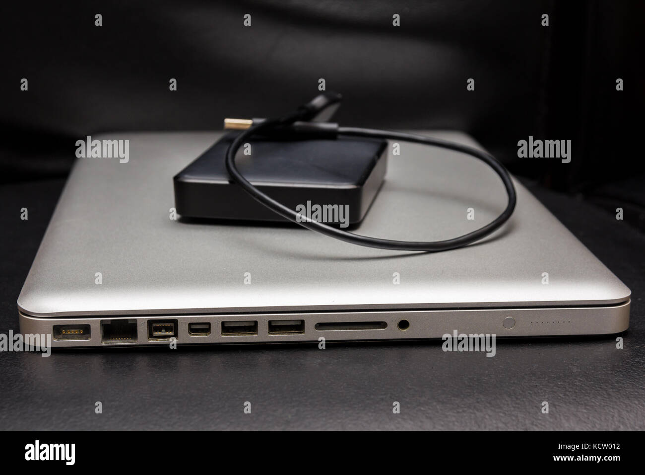 Silber Laptop mit externe Festplatte auf dunklen schwarzen Hintergrund Stockfoto