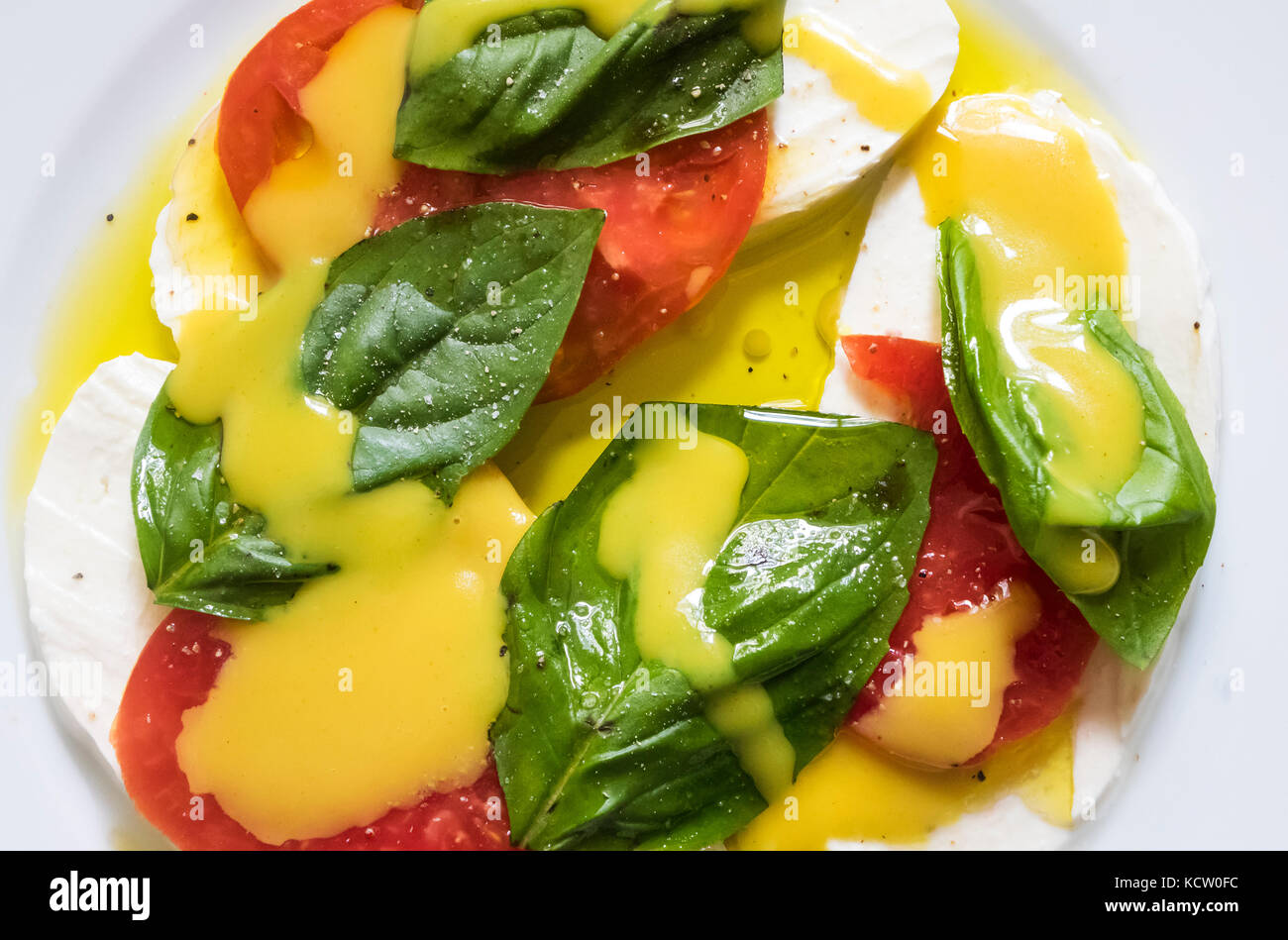 Nahaufnahme eines Caprese Salat: Mozzarella, Tomaten und frischem Basilikum mit Honig Senf Salat Dressing Stockfoto