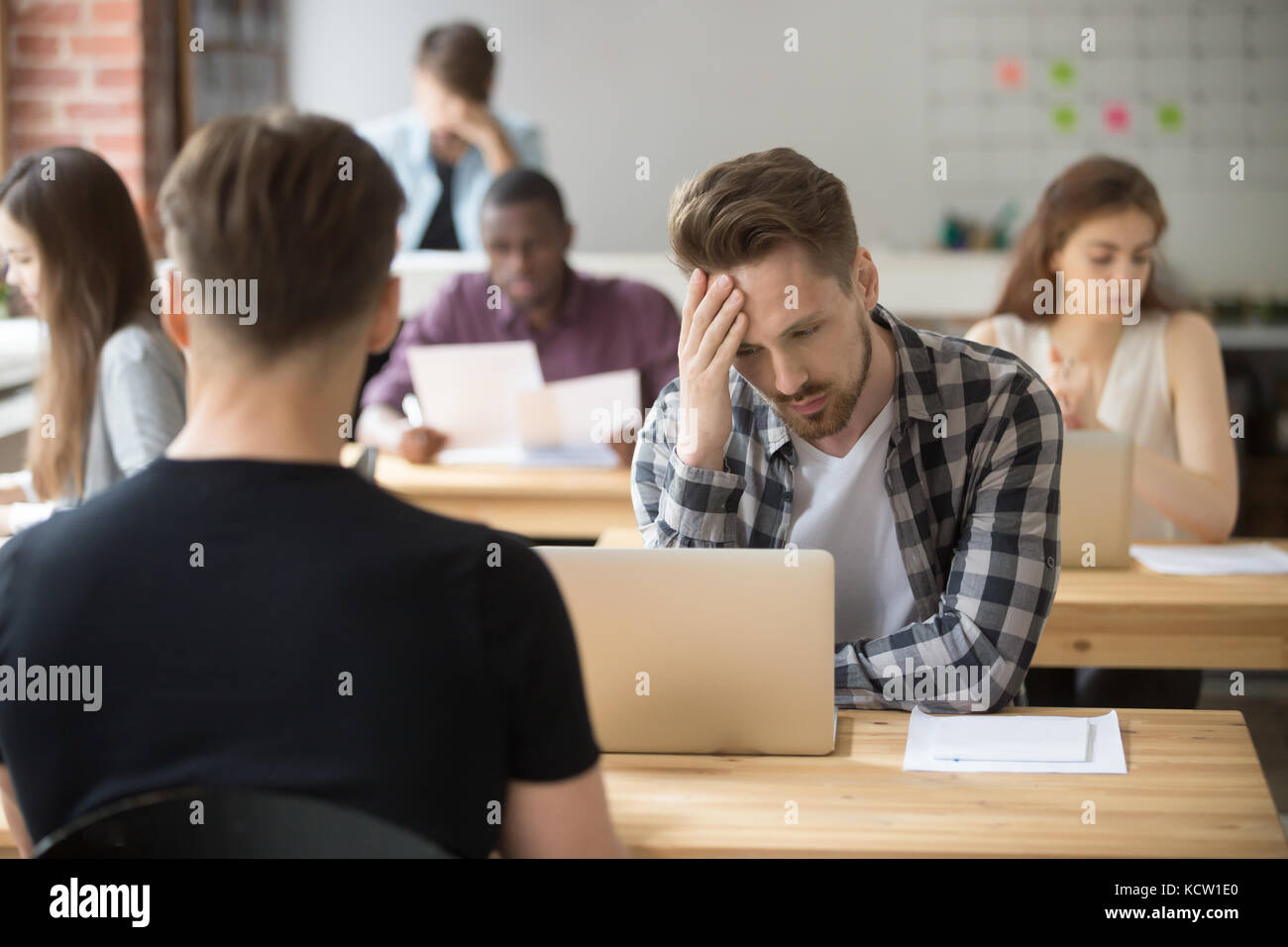 Ratlos und verwirrt casual Unternehmer sieht auf Laptop Bildschirm am Arbeitsplatz im Büro. junges Projekt Manager, schwerer Fehler, verlorene Dokument Stockfoto