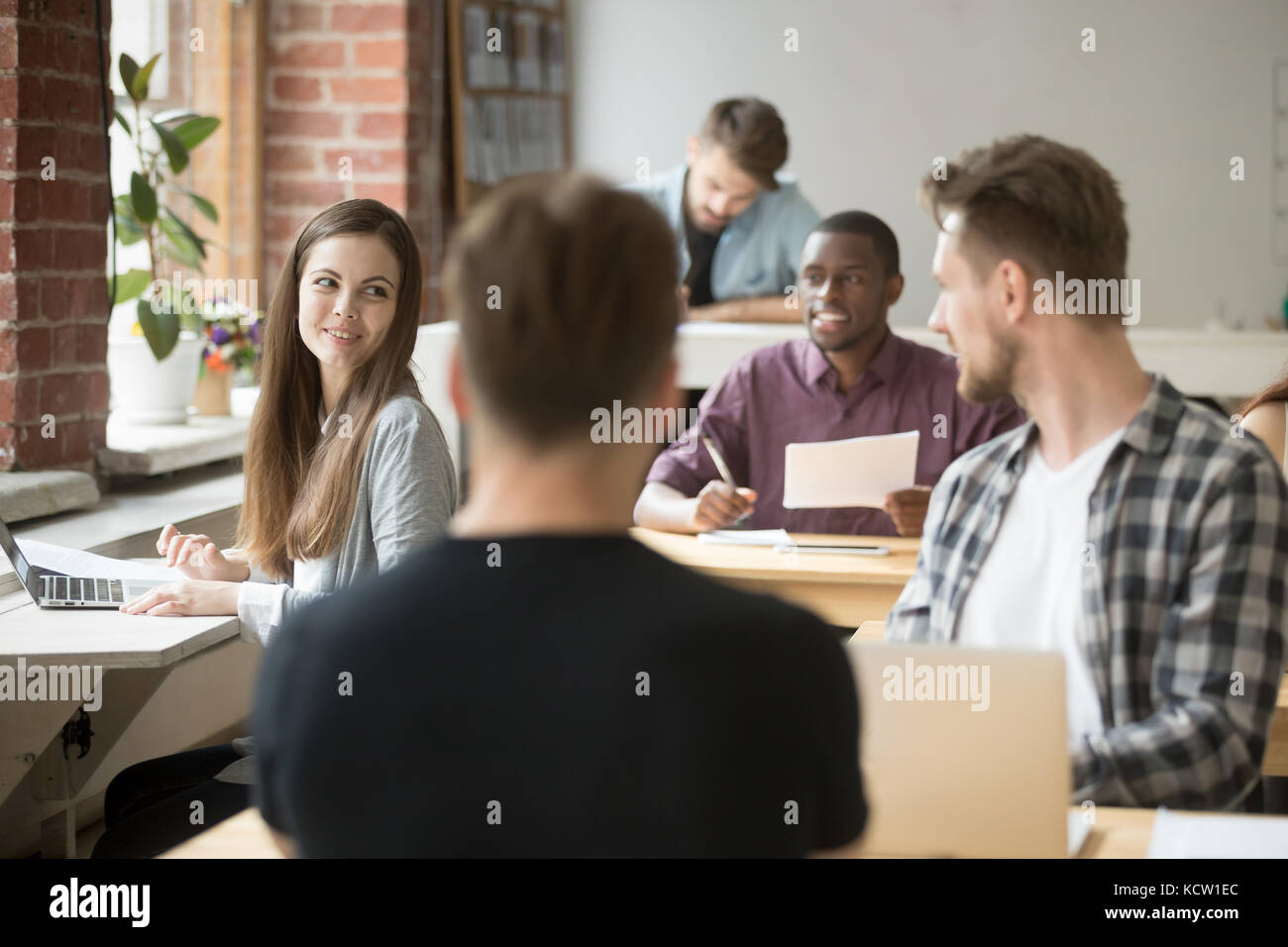 Weibliche Unternehmer im Gespräch mit einem der Mitarbeiter in Shared Office. Team von Kollegen während des Workflows kommunizieren, Mitarbeiter erkundigen über die Arbeit strate Stockfoto