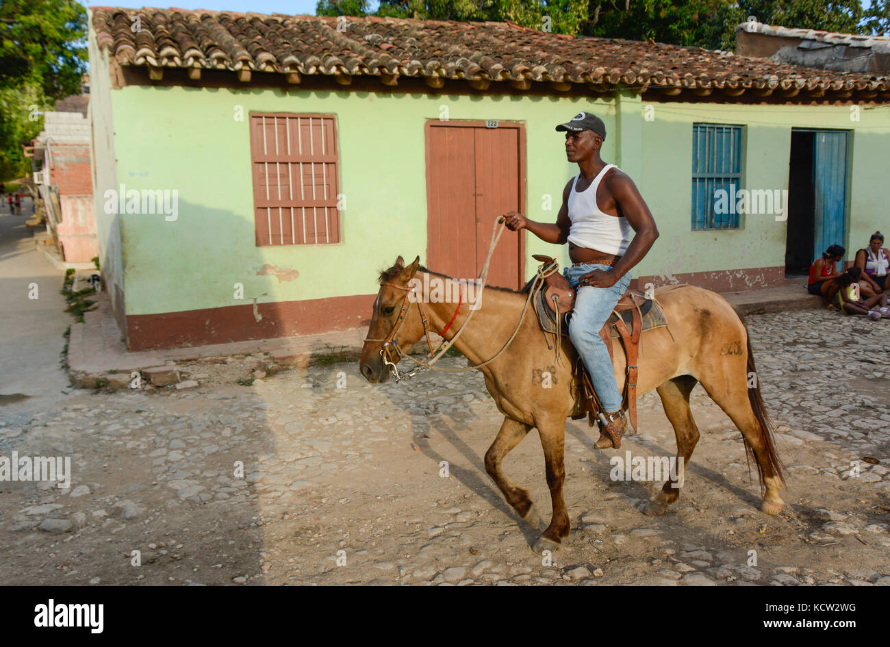 Resident mann Reiten durch die bunte Reihe der Häuser, Trinidad, Kuba Stockfoto