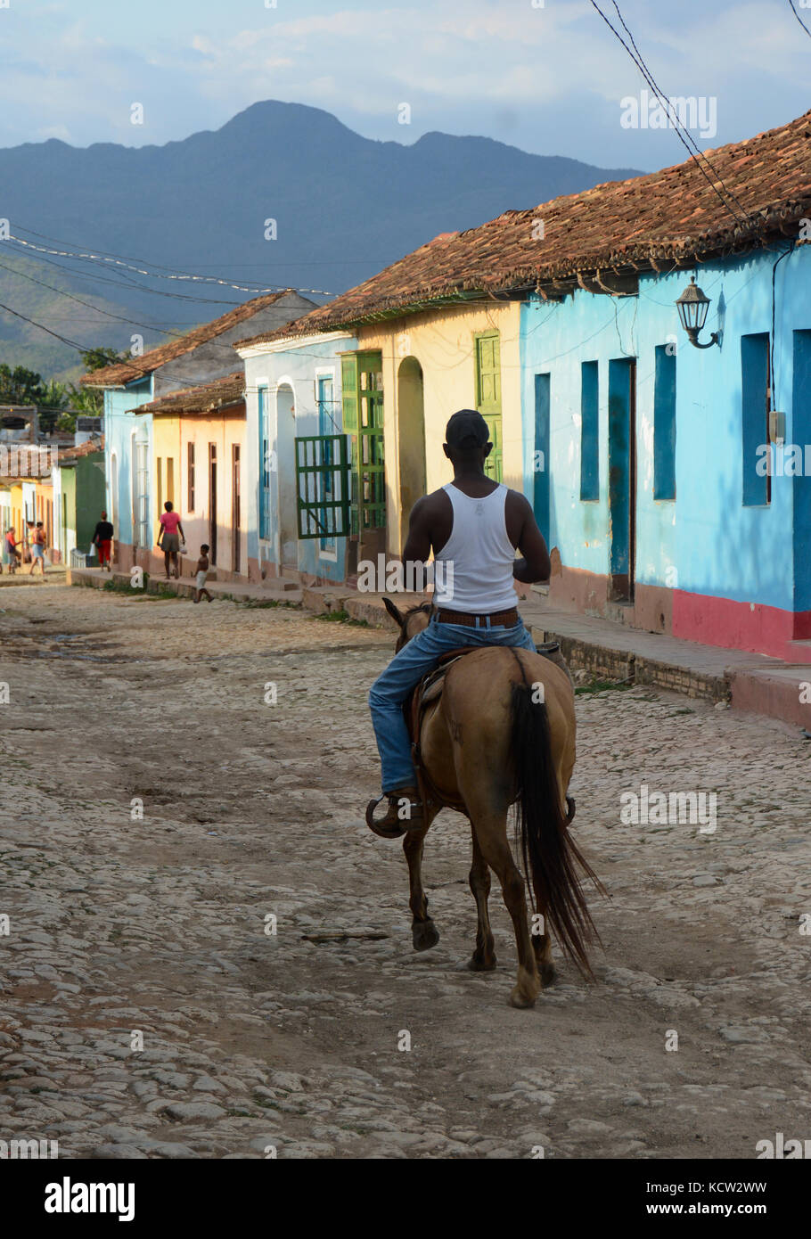 Resident mann Reiten durch die bunte Reihe der Häuser, Trinidad, Kuba Stockfoto