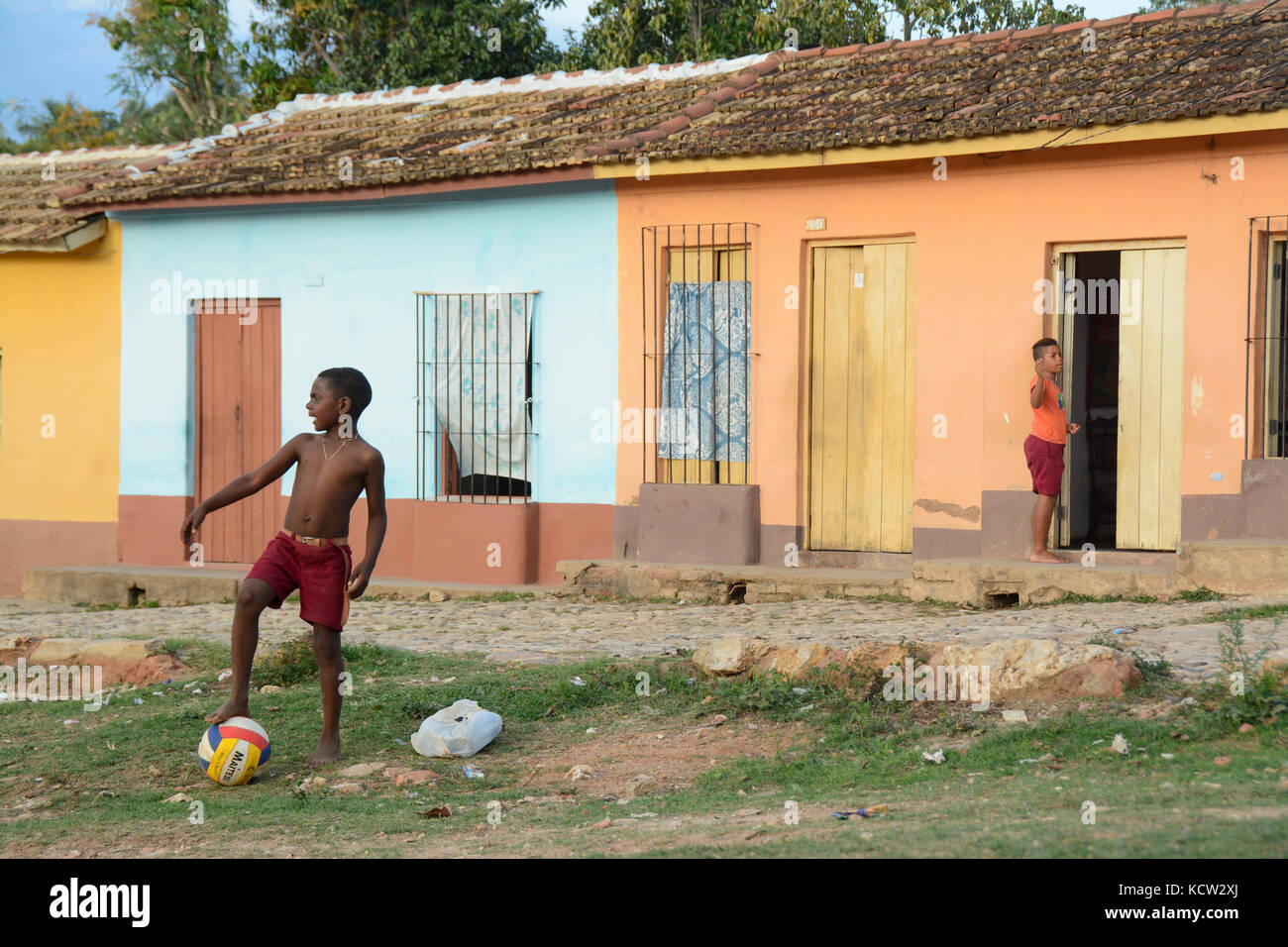 Junge spielt mit einem Ball in der Nähe eine Reihe von bunten Häusern, Trinidad, Kuba Stockfoto