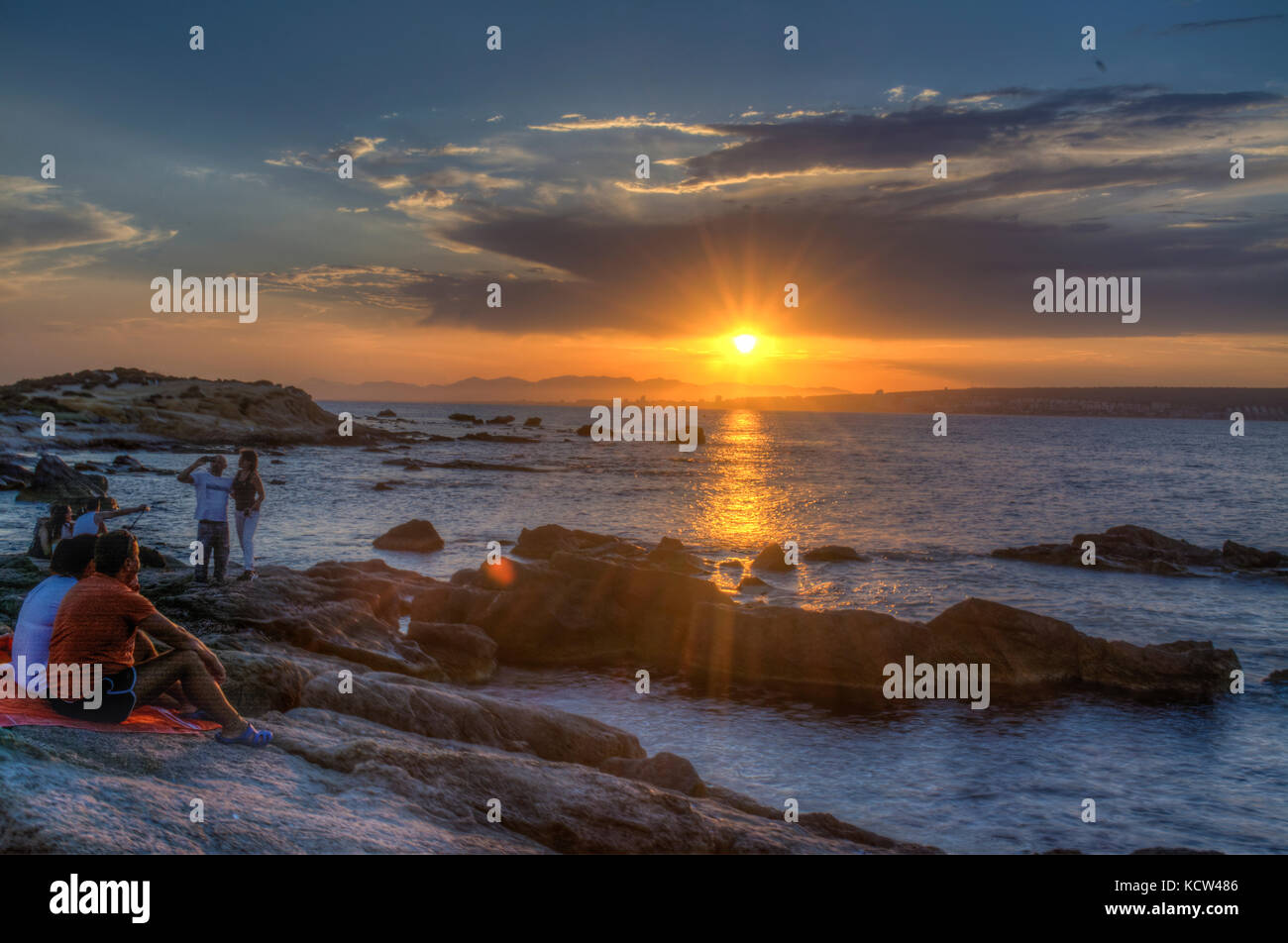 HDR-Bild von Menschen gerade der Sonnenuntergang über Felsen im Meer auf der spanischen Insel Tabarca Stockfoto