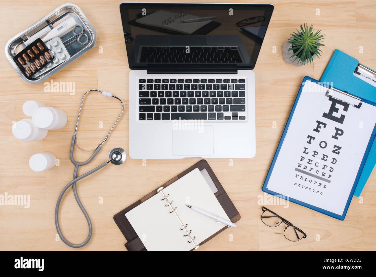 Draufsicht des Doktors Schreibtisch Tisch mit Stethoskop und Notebook mit einem Visual Test Chart Stockfoto