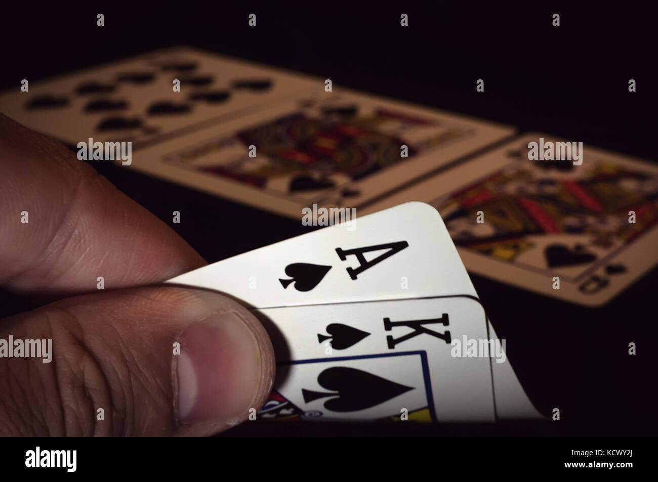 Zwei Karten sind Ass und König von Spaten in die Hand des Spielers im Poker, die Jack of Spades Dutzend liegen auf dem Tisch. Der poker Spieler das Glück, ein zu erhalten Stockfoto