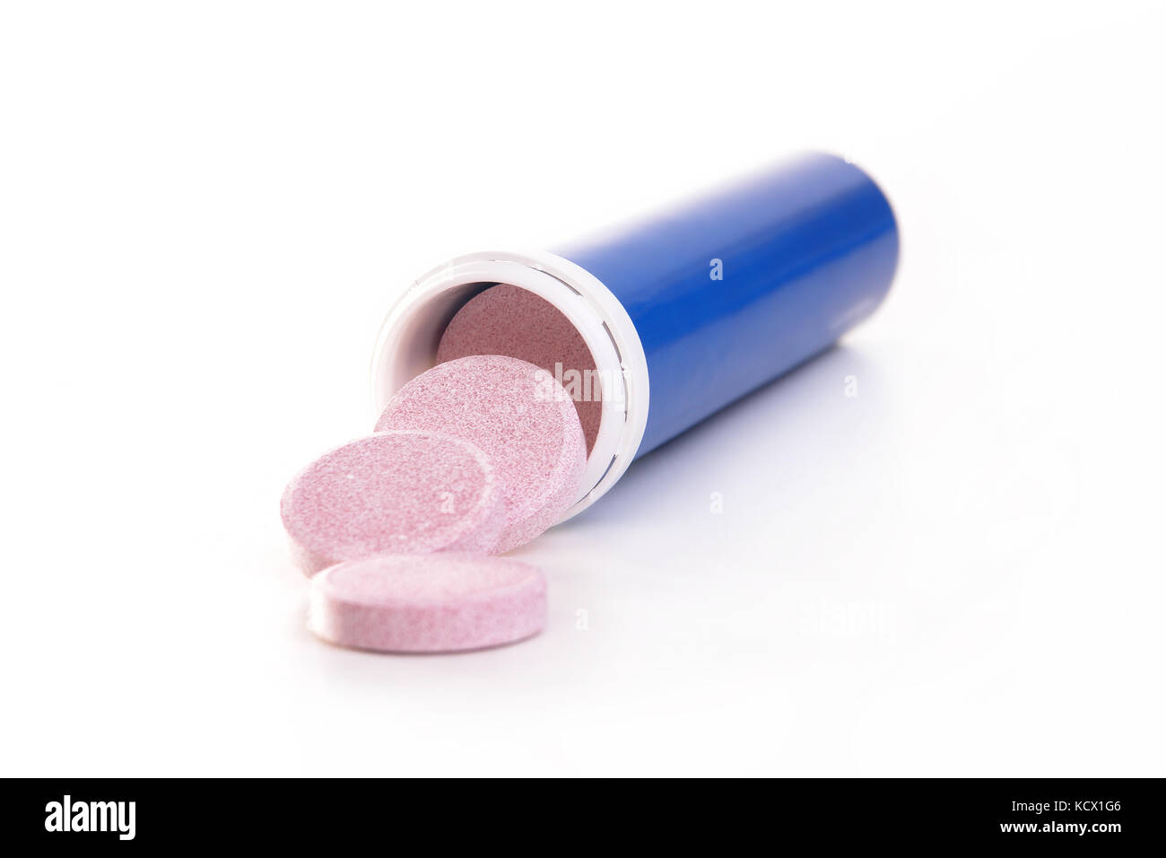 Drei rosa Tabletten verschütten aus blauen Container auf weißem Hintergrund Stockfoto