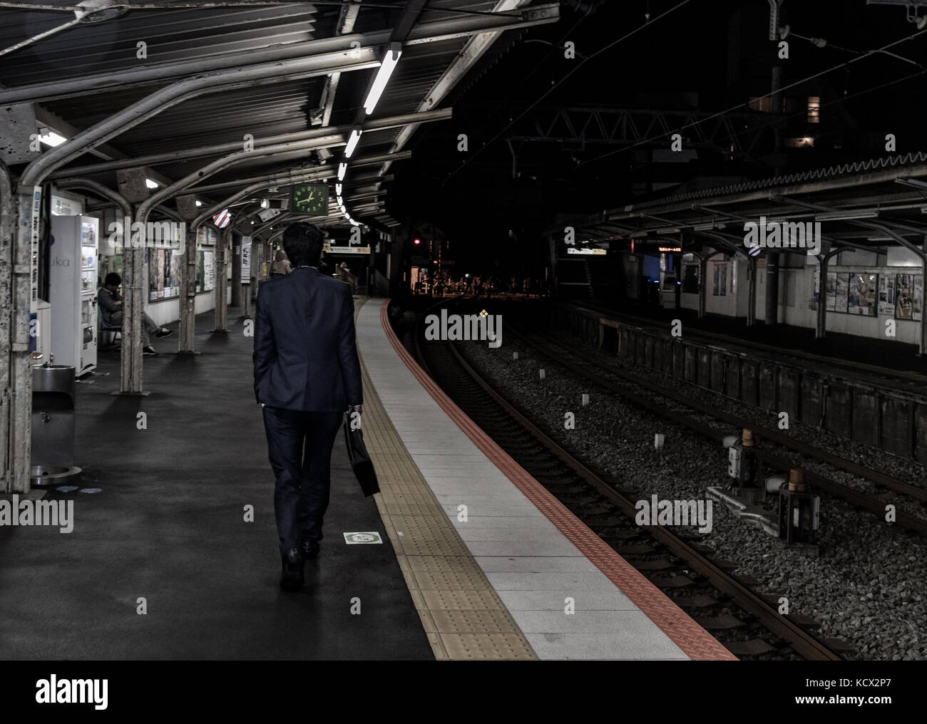 Eine Japanische Salaryman auf dem Heimweg von der Arbeit mitten in der Nacht. kann man die Zeit auf der Station. Stockfoto