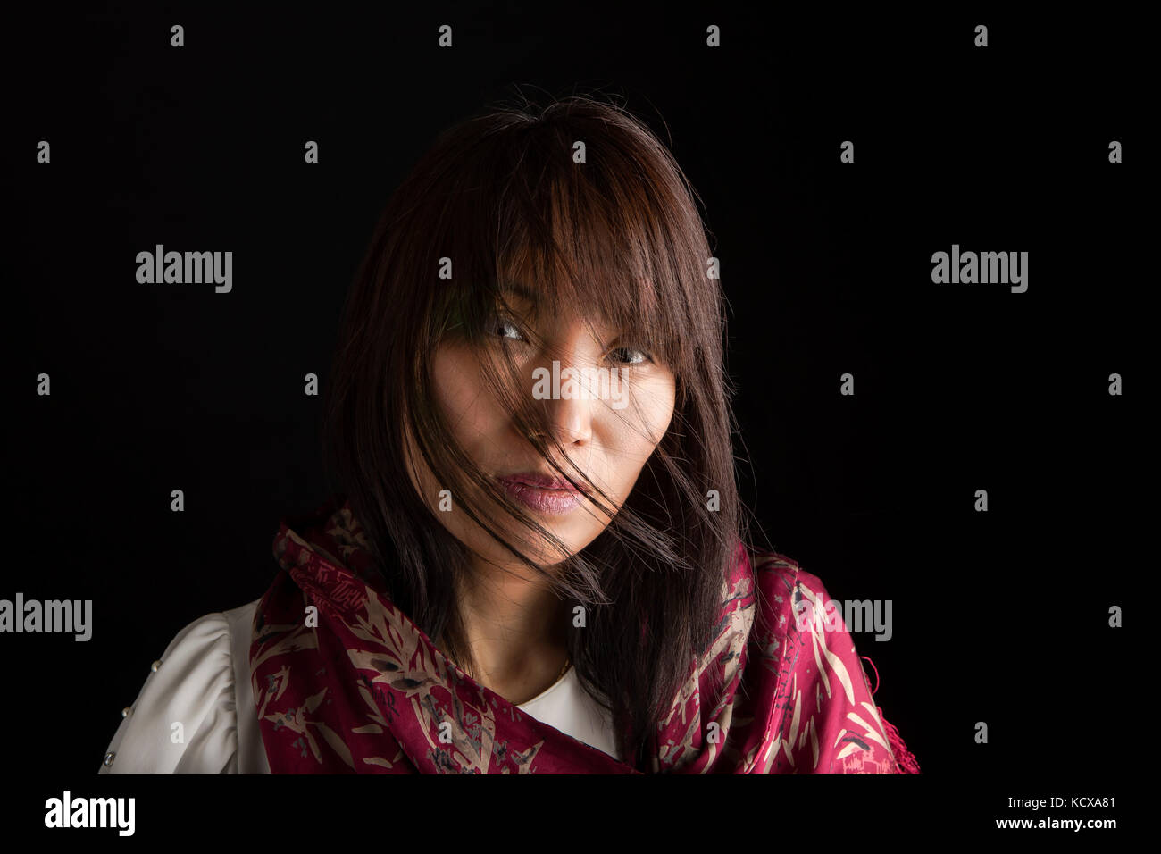 Eine Nahaufnahme Low Key portrait einer hübschen koreanische Frau mit einem Schal. Stockfoto