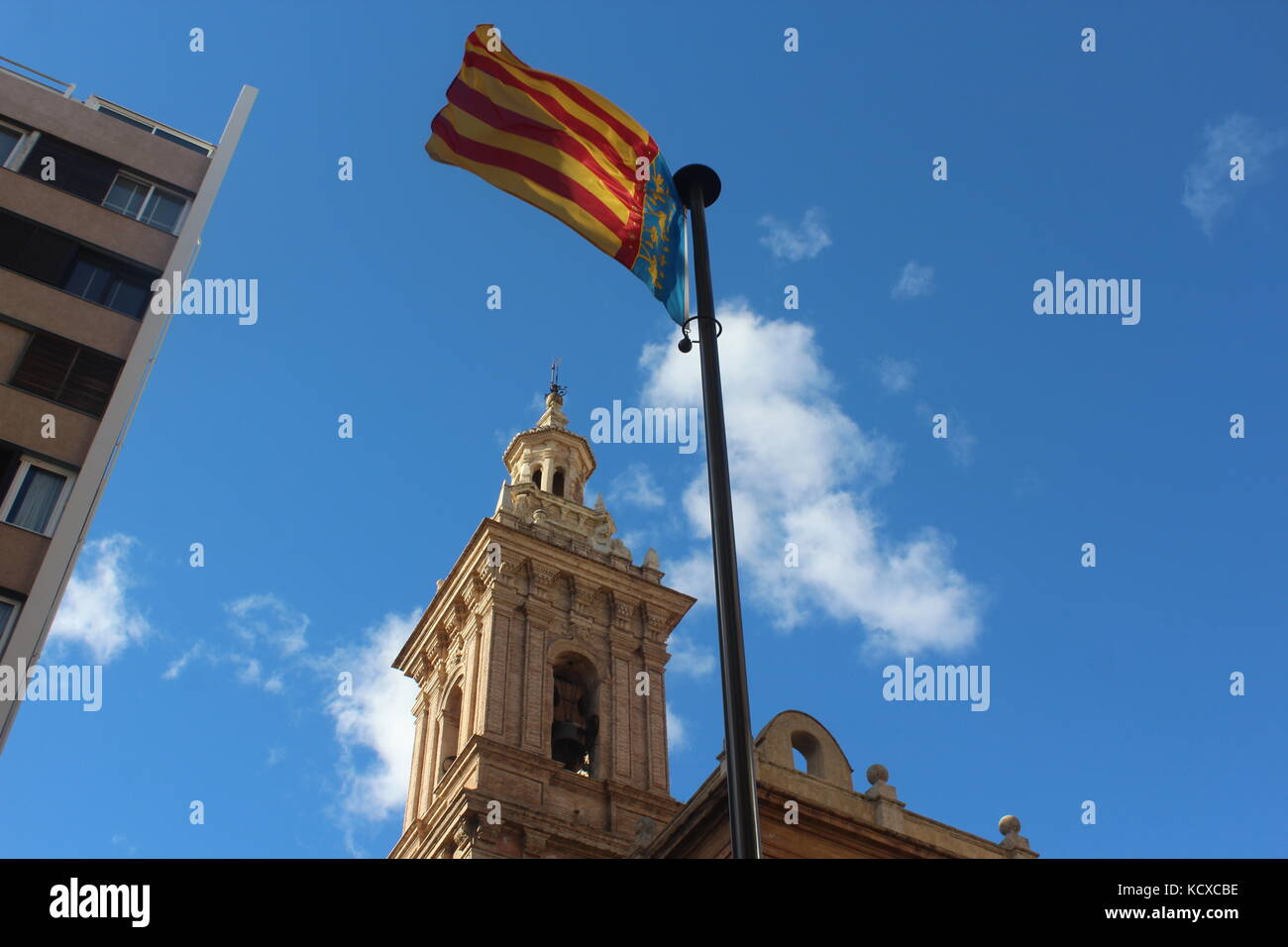 Die Flagge von Valencia weht im Wind unter blauen Himmel und Wolken. Stockfoto