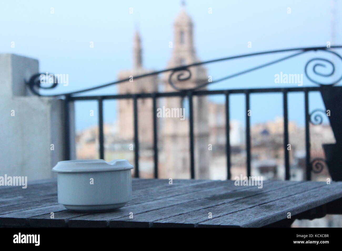 Weiß Aschenbecher auf Holztisch im Fokus, mit unscharfen Stadt im Hintergrund. Stockfoto
