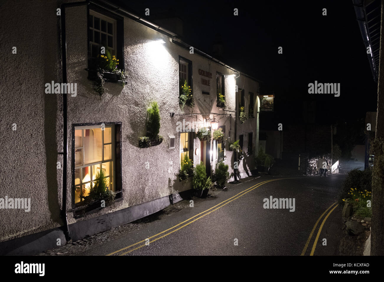 Walker vorbei Golden Rule Pub in der Nacht mit beleuchteten Schild, Kirstone Pass Road, Ambleside, Lake District National Park, Großbritannien Stockfoto