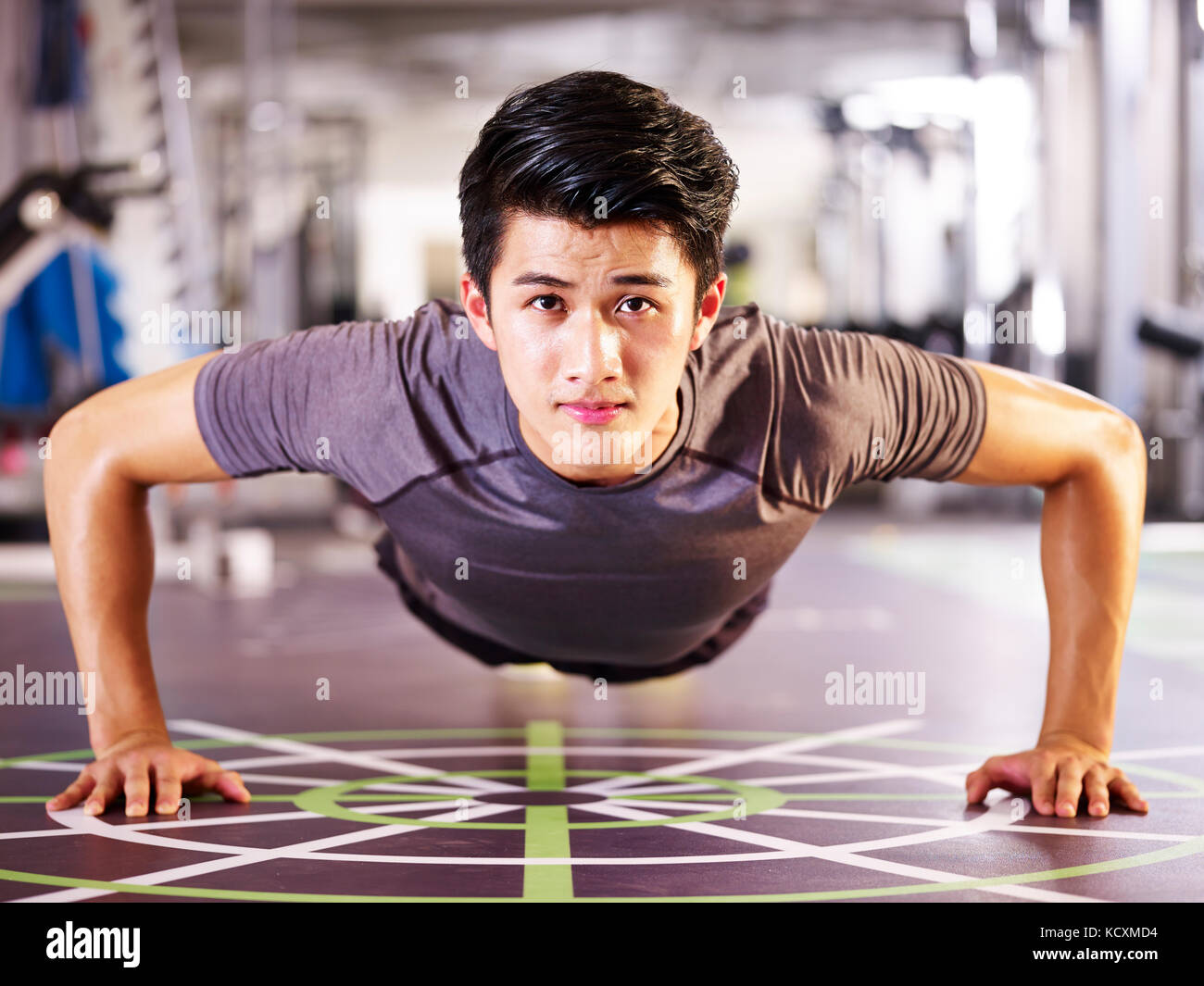 Jungen asiatischen erwachsenen Mann das Trainieren im Fitnessstudio tun pushups, frontale Ansicht. Stockfoto