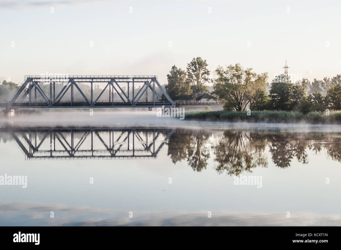 Eisenbahnbrücke oben misty See. Reflexion über die Wasseroberfläche. Stockfoto