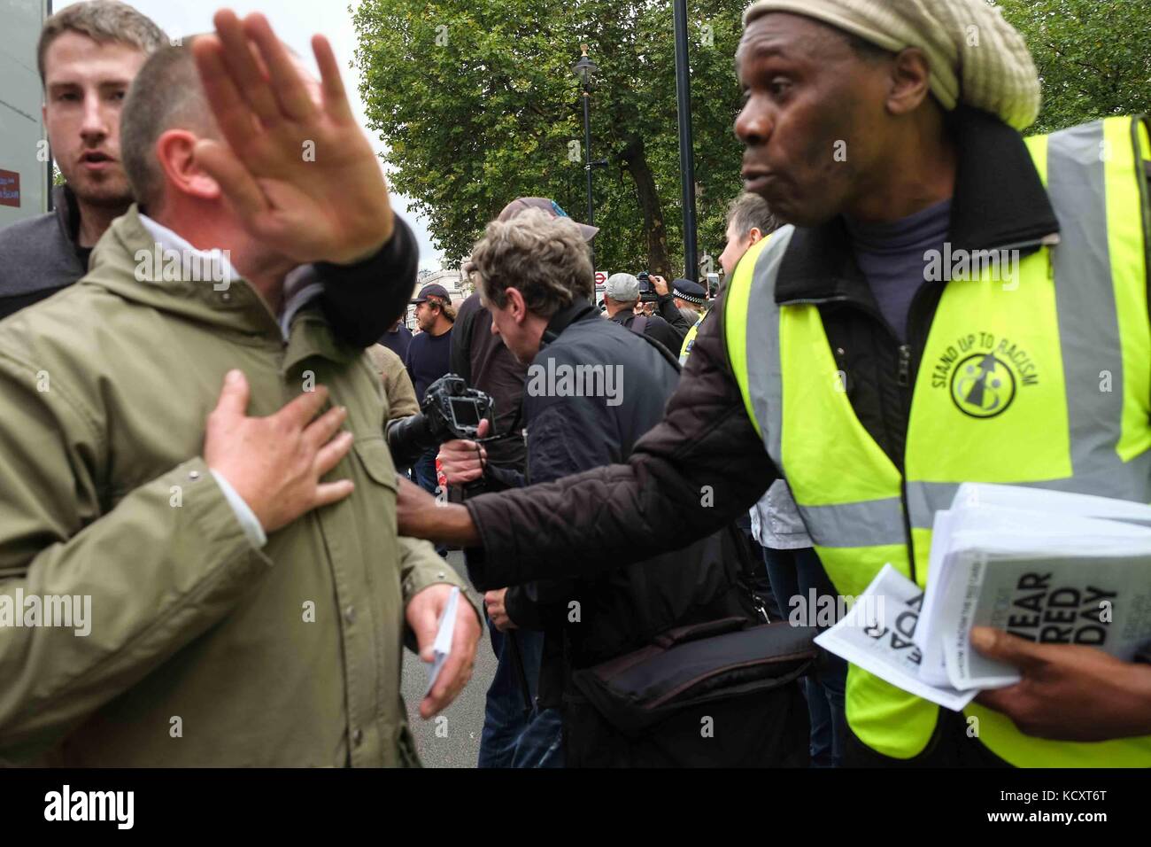 London, Großbritannien. 7. Okt 2017. Ein marcher spricht mit einem deomonstrater aus der Gruppe Stand bis zu Rassismus. Tausende Fußball-Fans aus ganz Großbritannien März entlang Whitehall gegen alle Formen von extremiasm. Die Fußball-Jungs Alliance wurde kurz nach den Terroranschlägen in Manchester und London Bridge. Credit: Claire Doherty/Alamy leben Nachrichten Stockfoto