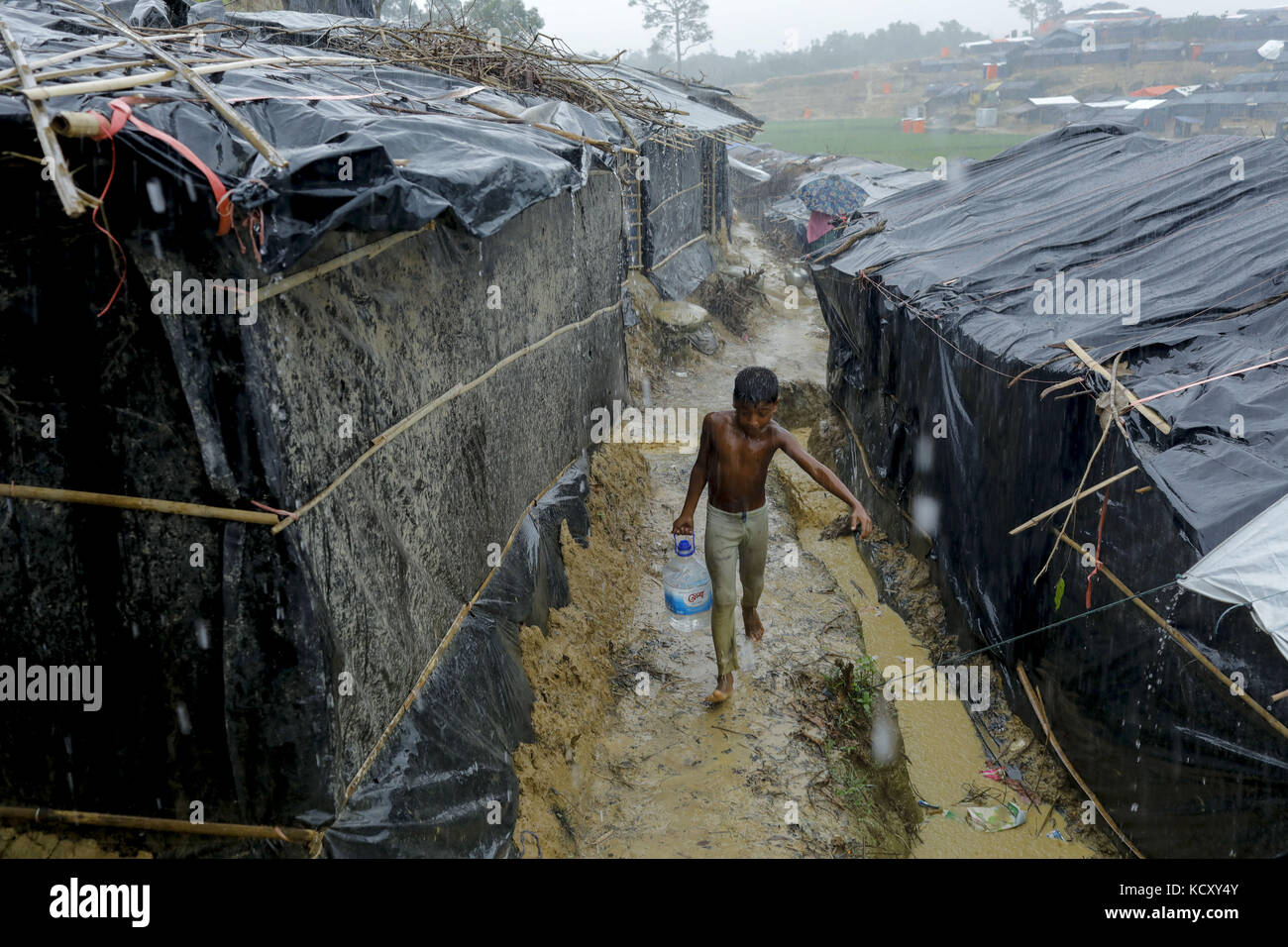 Ukhiya, Bangladesch. Oktober 2017. Rohingya Flüchtlingsjunge trägt Trinkwasser bei starkem Regen, der aus dem Staat Myanmar Rakhine auf Ukhiya, Cox's Bazar, kommt. Nach Angaben des UNHCR sind im letzten Monat mehr als 500.000 Rohingya-Flüchtlinge vor der Gewalt in Myanmar geflohen, die meisten versuchten, die Grenze zu überqueren und Bangladesch zu erreichen. Kyaw Tint Swe, der Minister für das Amt des Staatsrats Myanmars, besuchte Bangladesch und stimmte zu, die Rohingyas nach gegenseitigem Einvernehmen mit der Regierung Bangladeschs zurückzuholen. Quelle: K M Asad/ZUMA Wire/Alamy Live News Stockfoto