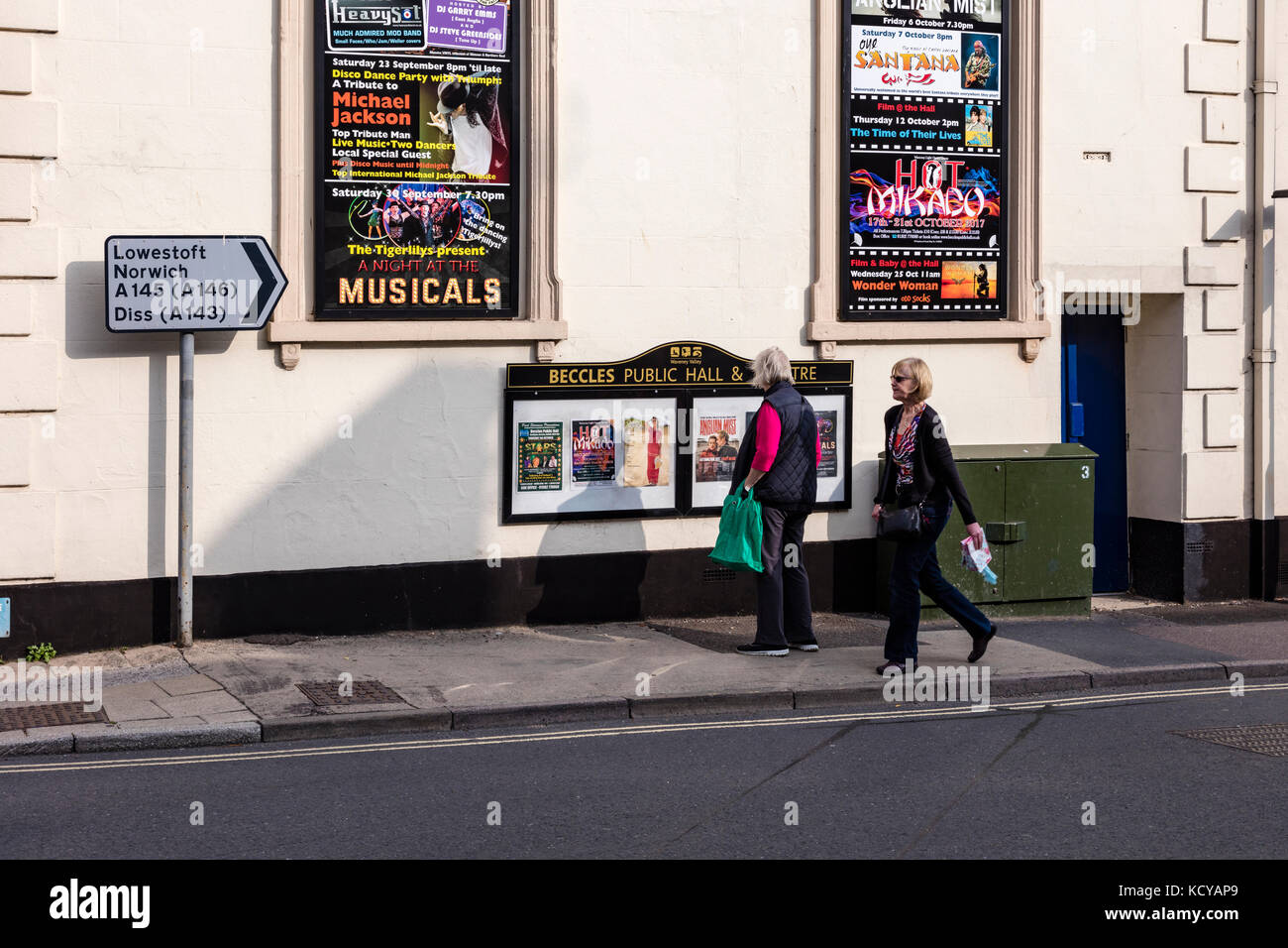 Eine Frau sieht Poster an der Wand von beccles öffentlichen Hall und Theater, Beccles, Suffolk, Großbritannien Stockfoto