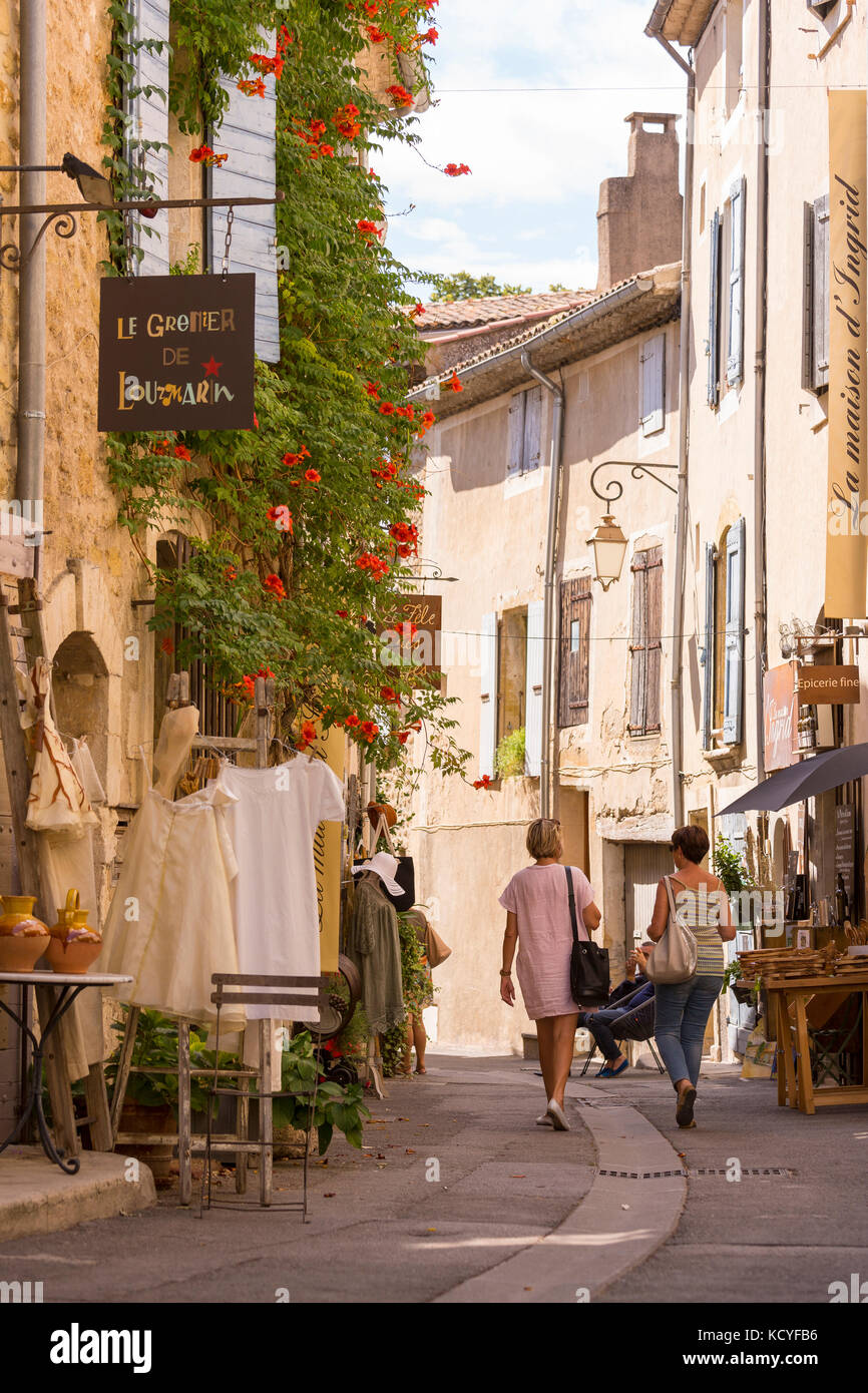 In Lourmarin, Provence, Frankreich - zwei Frauen gehen auf schmalen stret von Geschäften, Lourmarin, einem Dorf in der Landschaft von Luberon, Region Vaucluse. Stockfoto