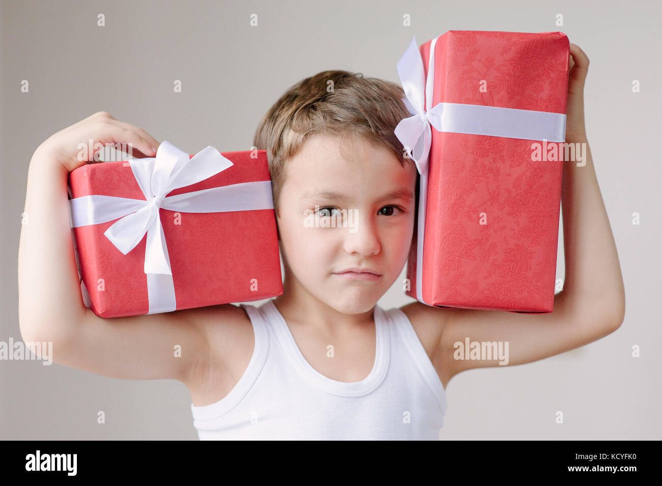 Junge mit zwei Kisten voller Geschenke auf seinen Schultern Stockfoto