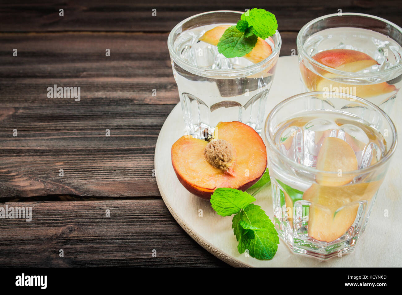 Wasser mit Pfirsiche auf einem hölzernen Hintergrund. Stockfoto