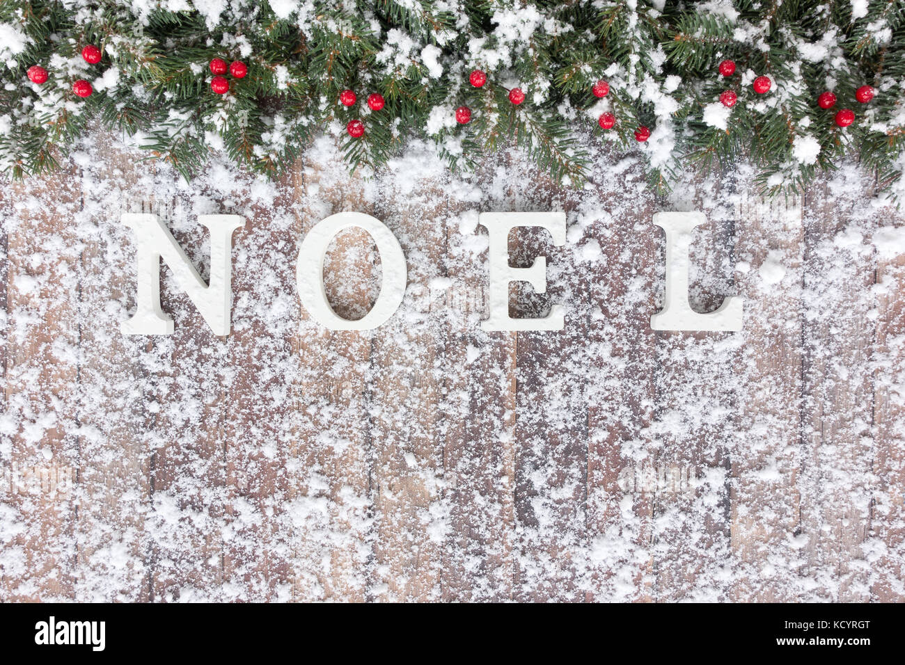 Weihnachten Grenze aus der verschneiten Natur Weihnachtsbaum tanne Zweige, roten Beeren und Noel mit weißem Holz Buchstaben geschrieben auf braunem Holz- backgrou Stockfoto
