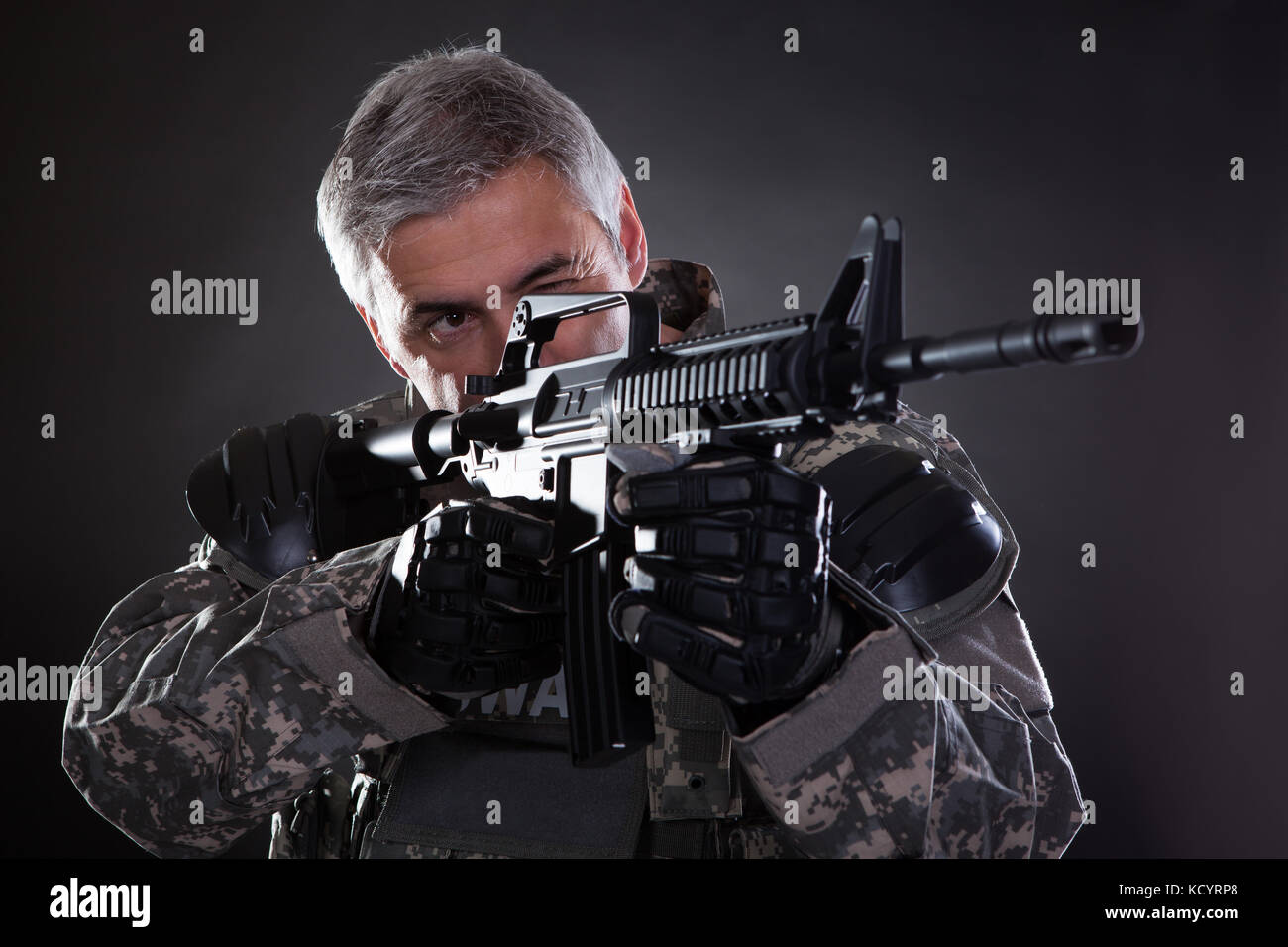 Porträt eines ausgereiften Soldaten mit Gewehr über schwarzen Hintergrund mit dem Ziel Stockfoto