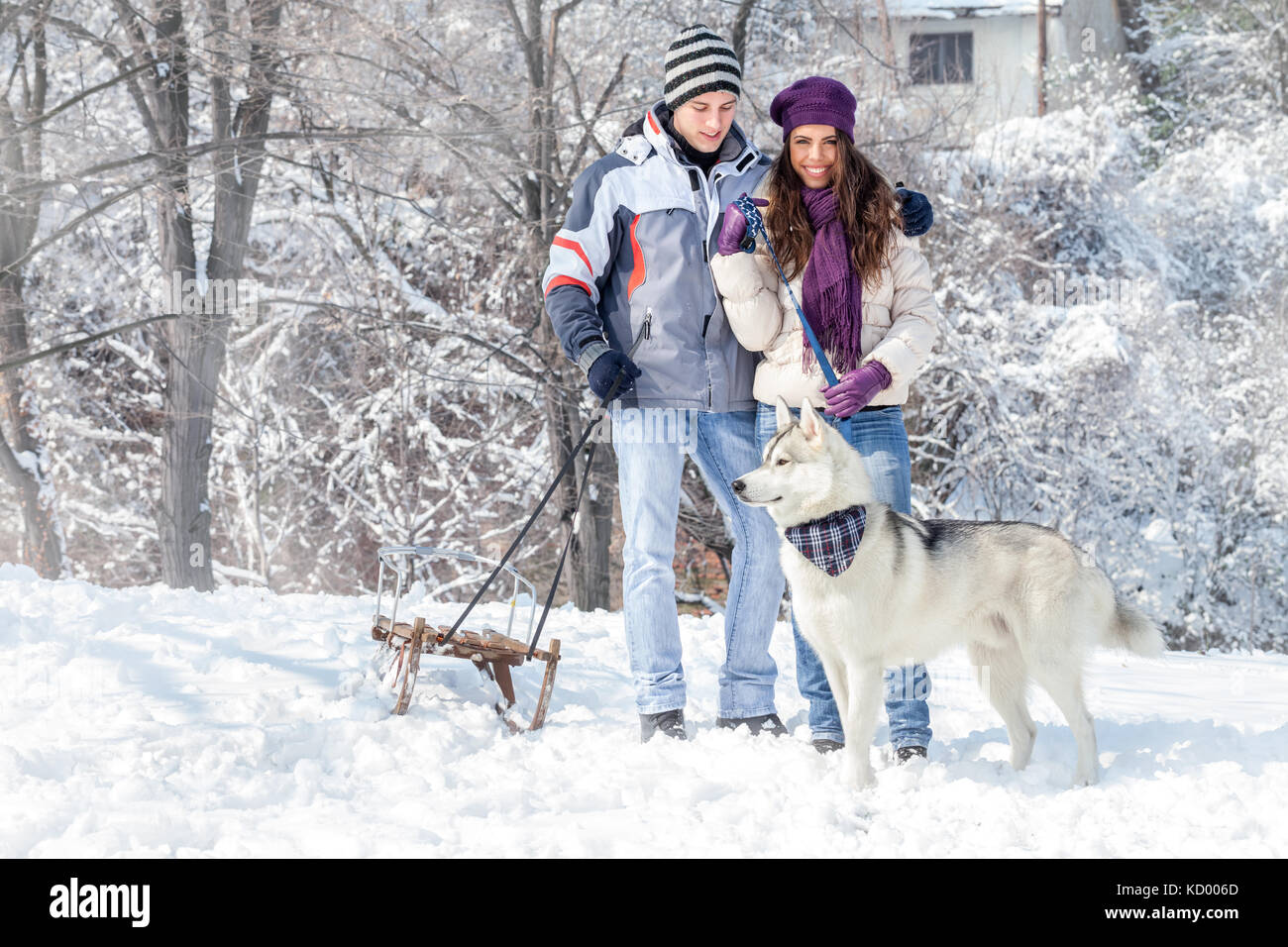 Junges Paar mit seinem Hund im verschneiten Wald Stockfoto