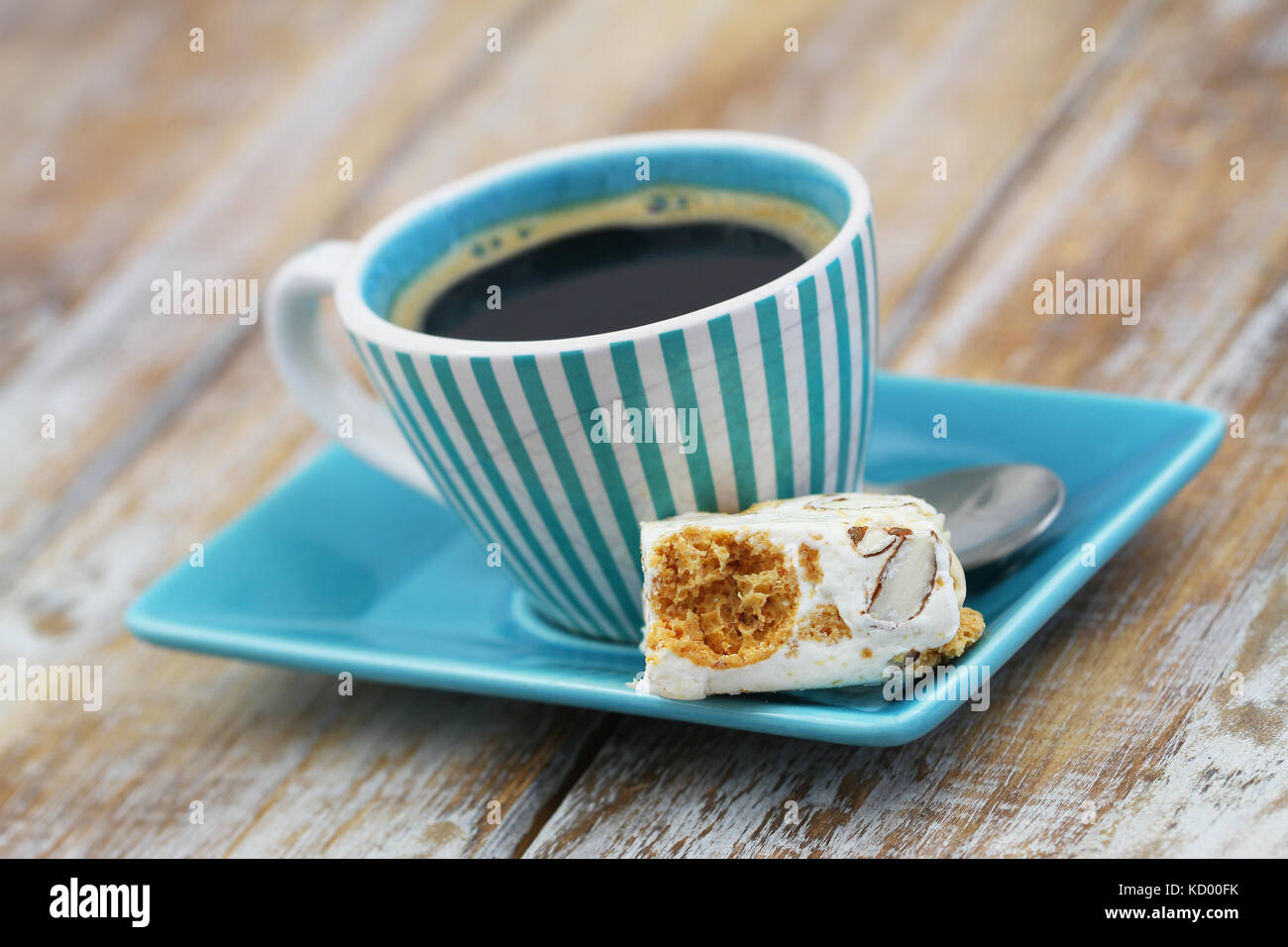 Stück leckeren Soft Nougat mit Tasse schwarzen Kaffee auf Holzmöbeln im Landhausstil Oberfläche Stockfoto