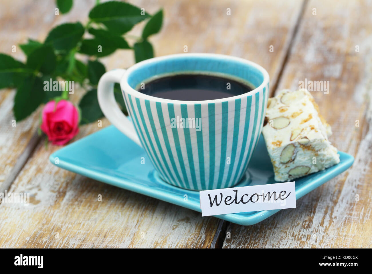 Welcome Card mit Tasse Kaffee, süße Nougat und pink Wild Rose auf Holzmöbeln im Landhausstil Oberfläche Stockfoto