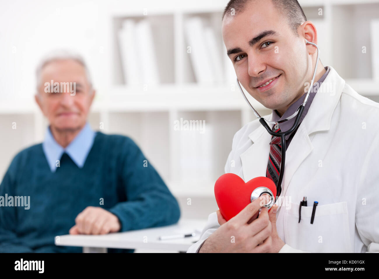 Arzt halten roten Herzen Symbol mit Patienten im Hintergrund Stockfoto