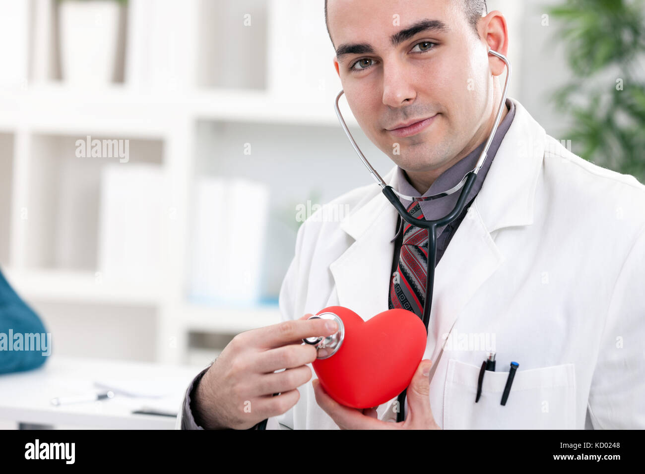 Junge Kardiologen halten roten Herzen und Stethoskop Stockfoto